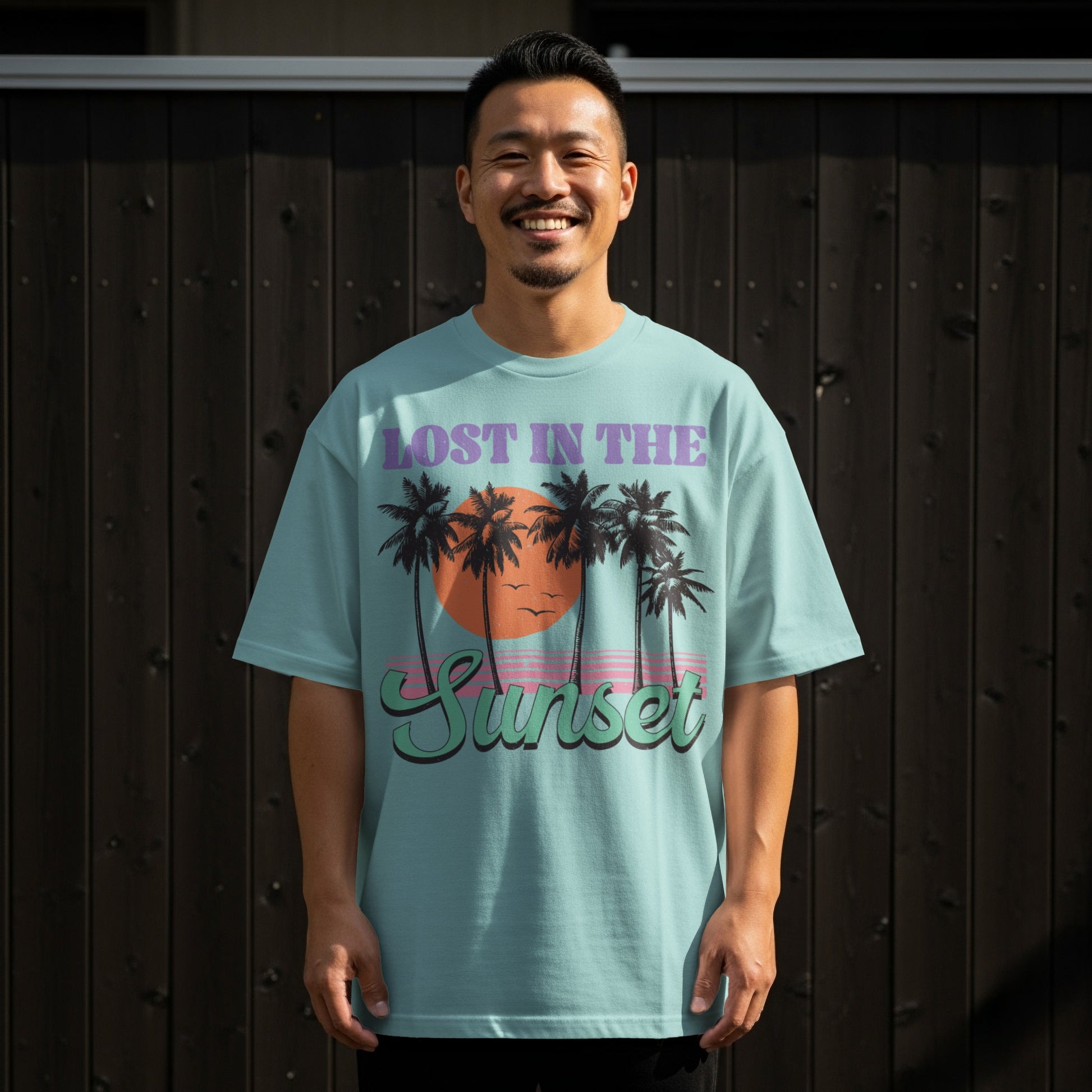 Man wearing a light blue t-shirt with a "Lost in the Sunset" graphic.