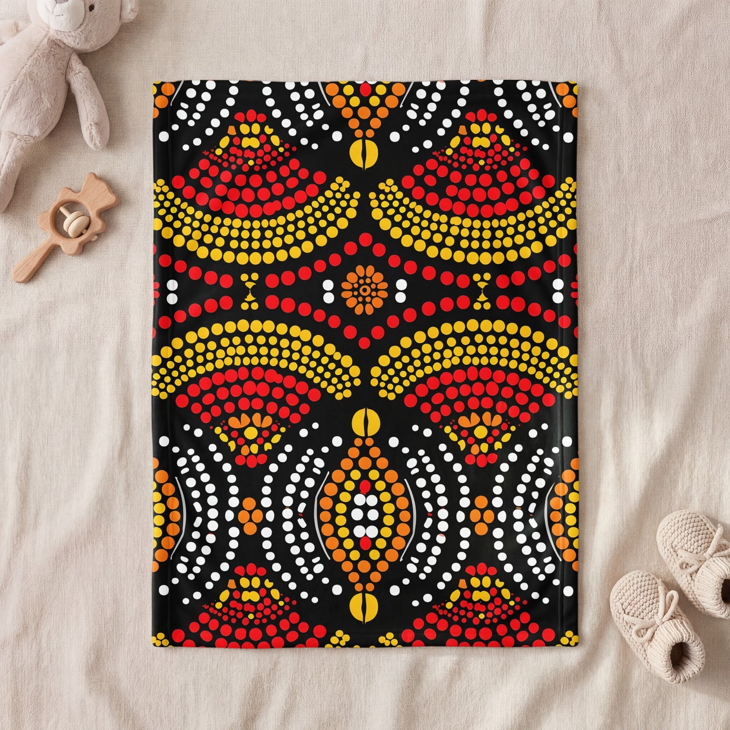 Black blanket with Indigenous dot art in red, yellow, orange, and white.