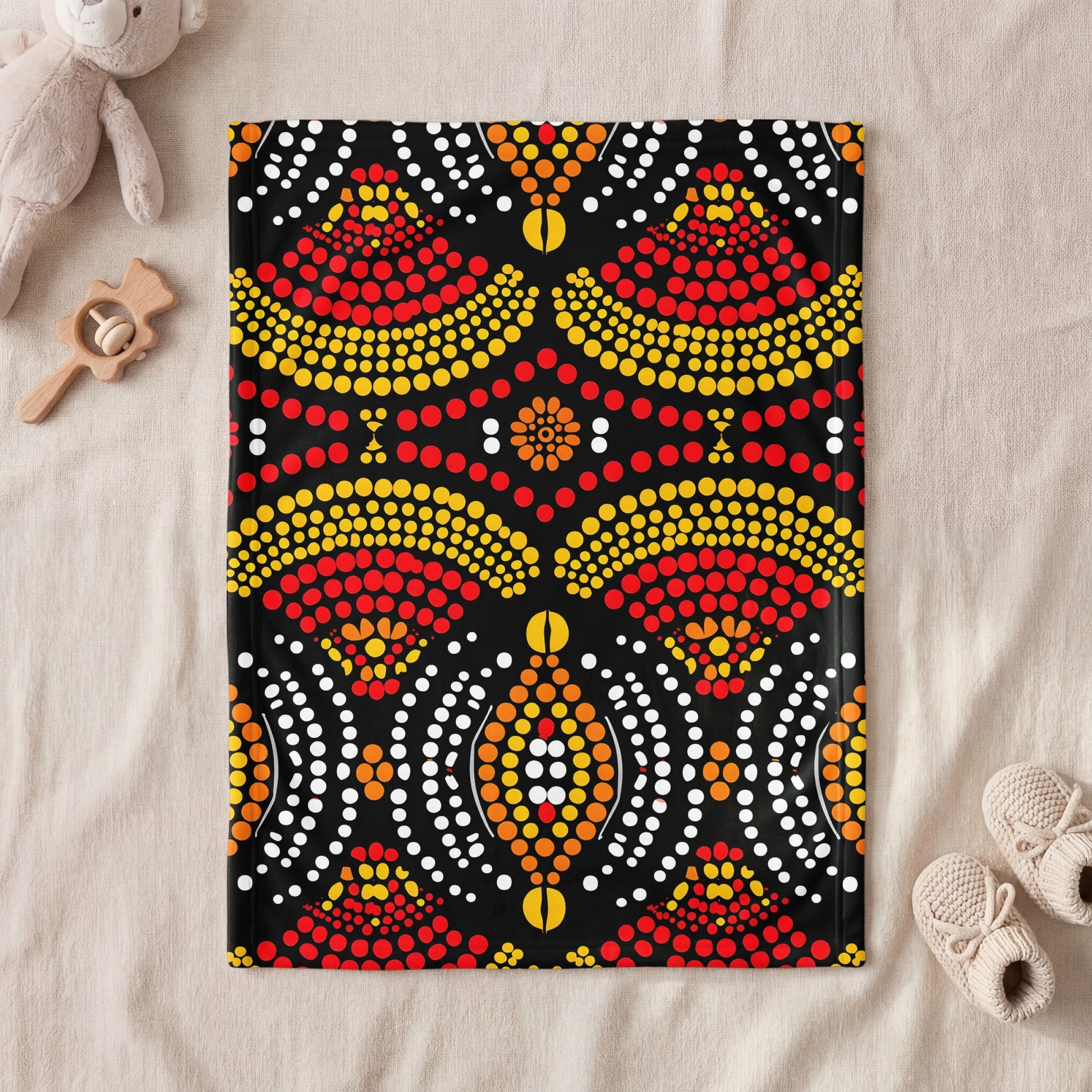 Black blanket with Indigenous dot art in red, yellow, orange, and white.