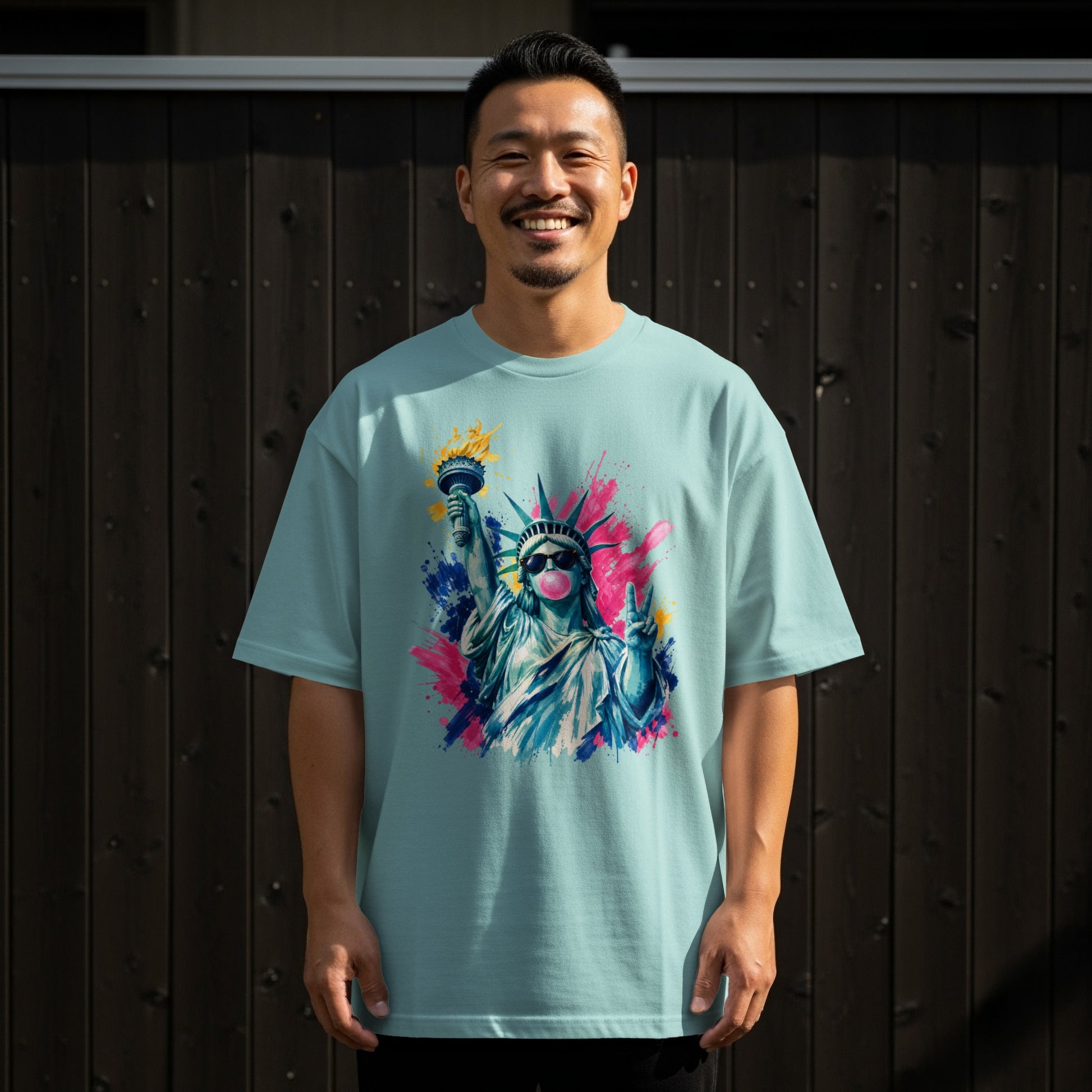 Man in light blue t-shirt with Statue of Liberty graphic and pink bubblegum.