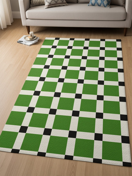 Green, black, and white checkerboard rug on a hardwood floor next to a sofa.