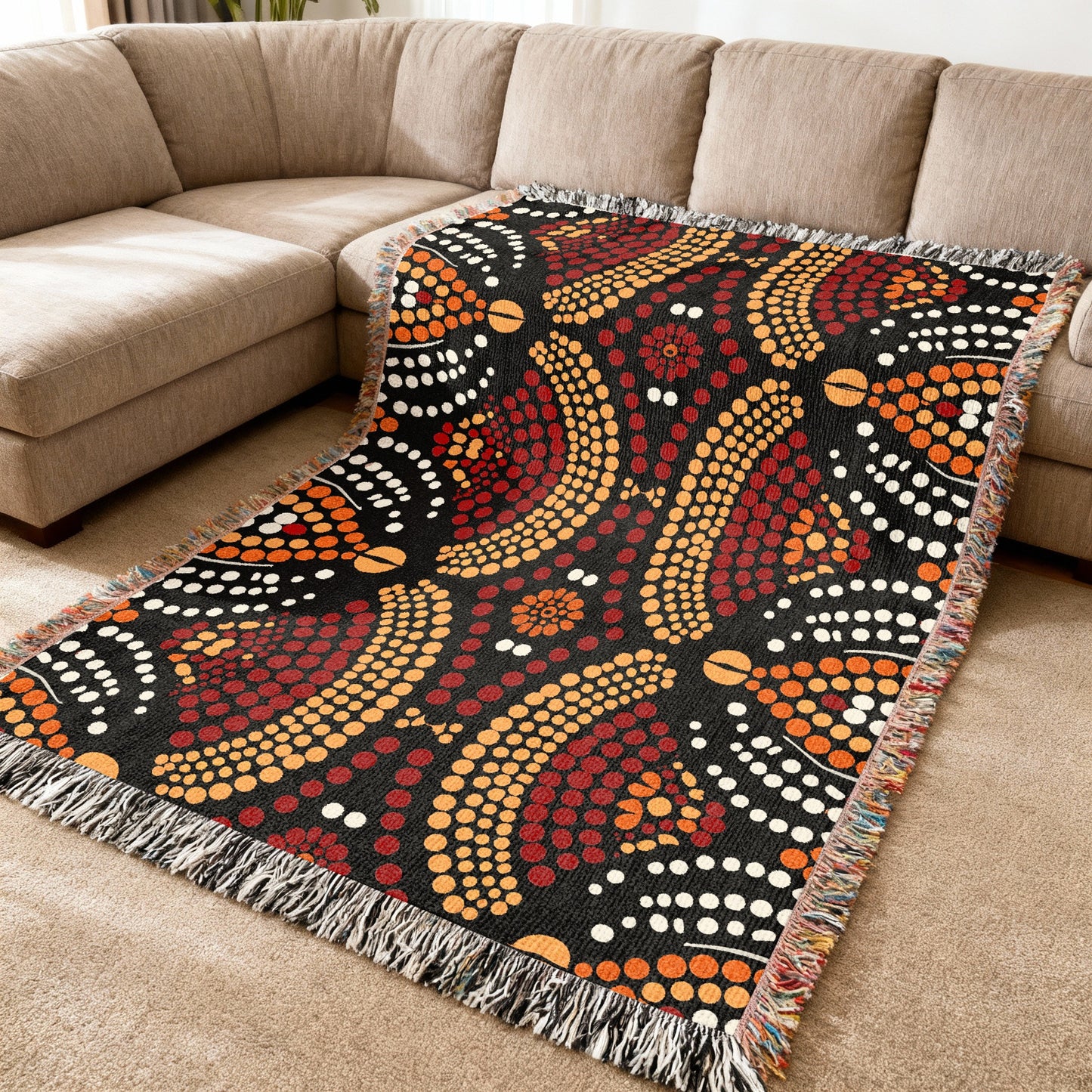 Throw blanket with a black background featuring a dot art pattern in red, orange, and white.