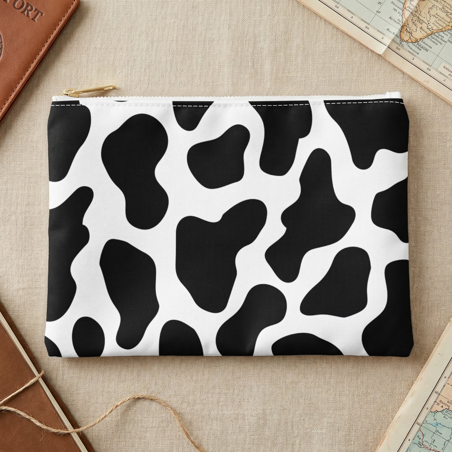 Clutch bag with black and white cow print pattern and gold zipper.