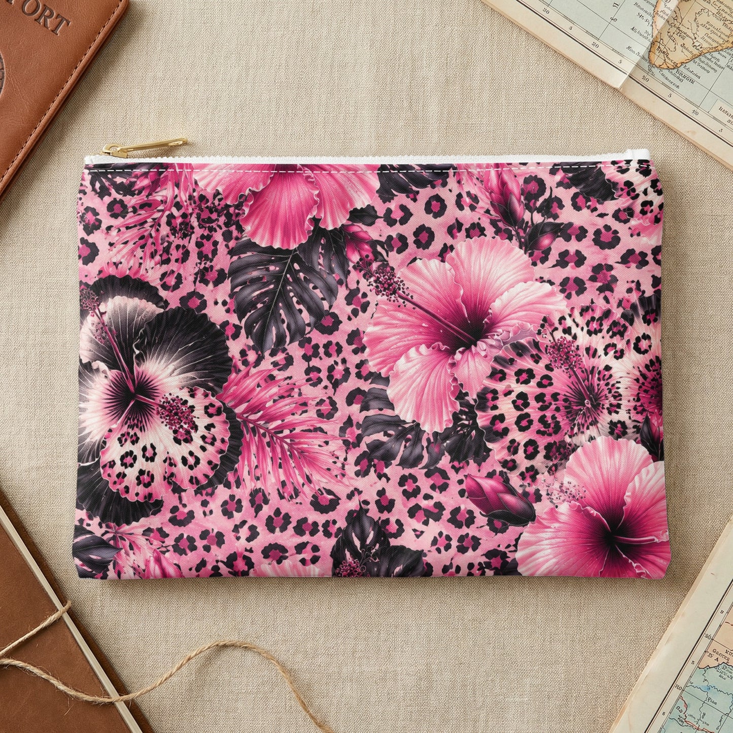 Pink hibiscus and leopard print clutch with a gold zipper against a beige background.