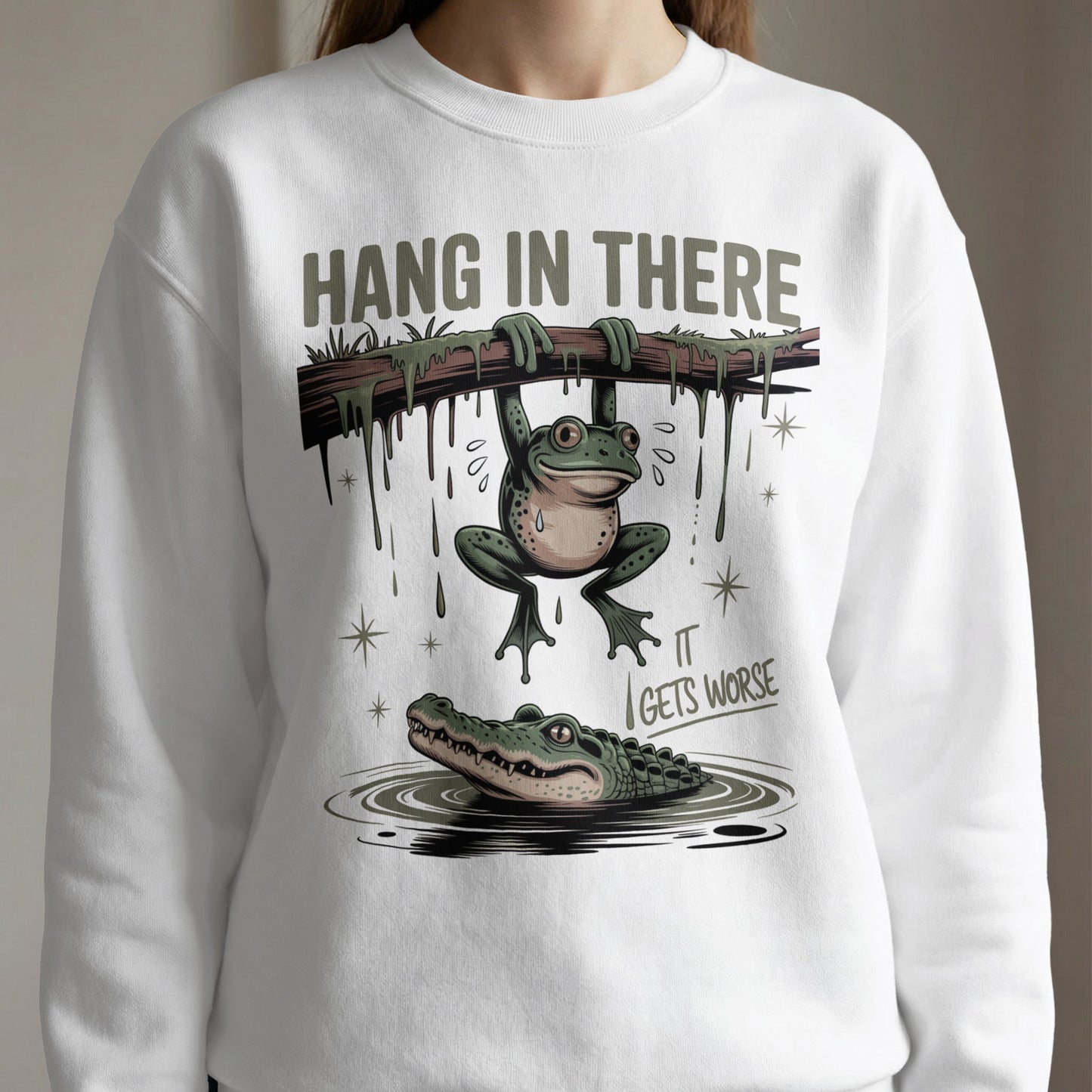 Frog hanging from branch over alligator, text "Hang in there it gets worse".