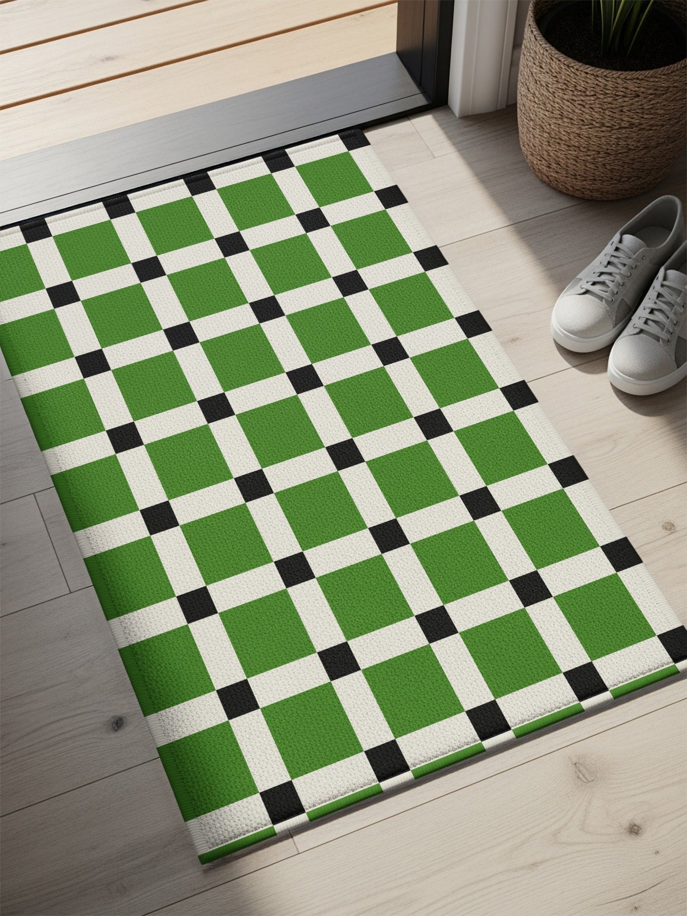 Green and white checkered doormat with black squares, on a wooden floor.