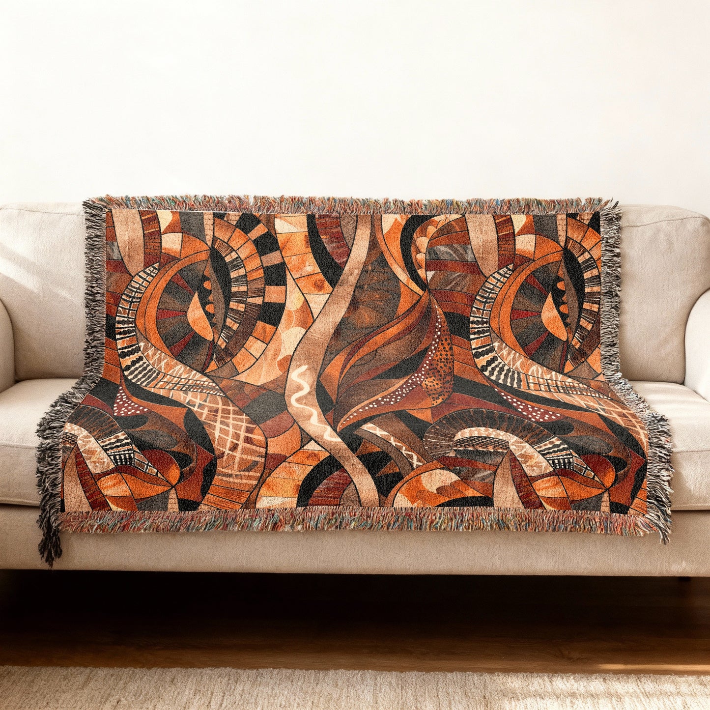 Couch with a brown abstract patterned throw blanket with fringed edges.