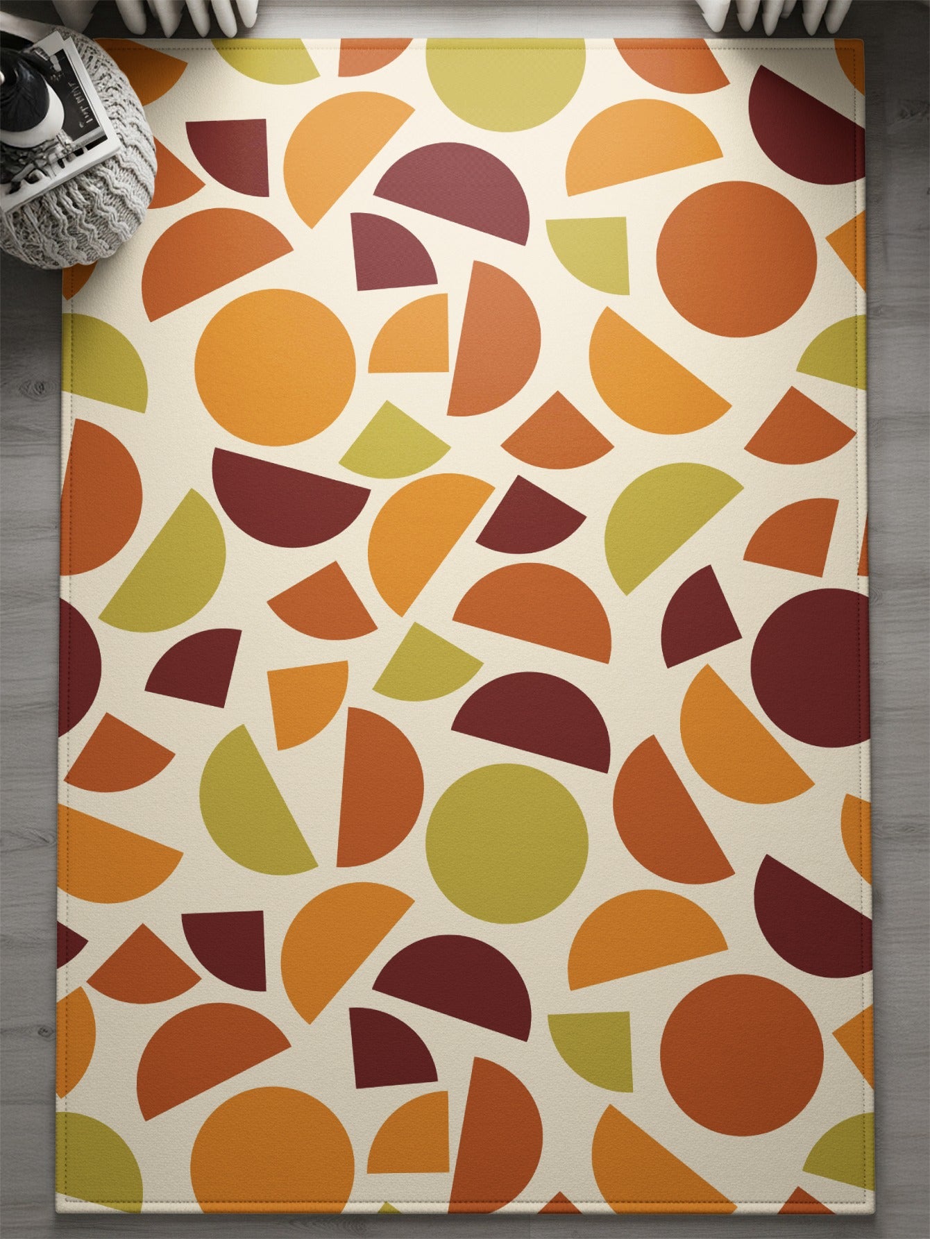 Tapestry rug with scattered geometric shapes in orange, burgundy, and olive green.