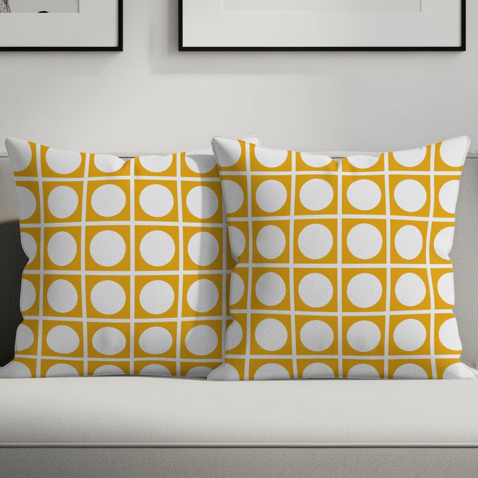 Two mustard yellow throw pillows with a white geometric circle pattern on a sofa.