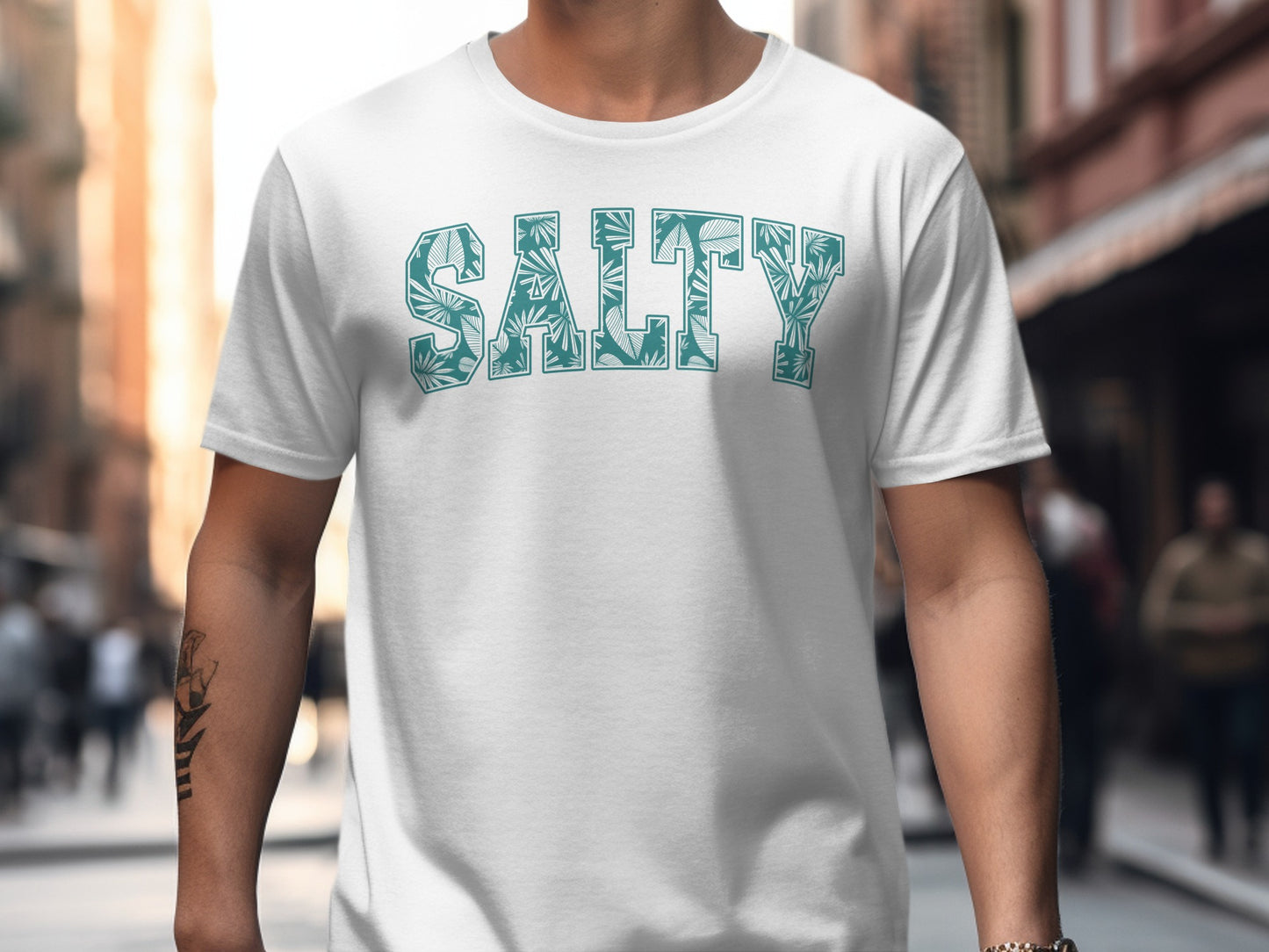 White t-shirt with "SALTY" text in a tropical leaf pattern.