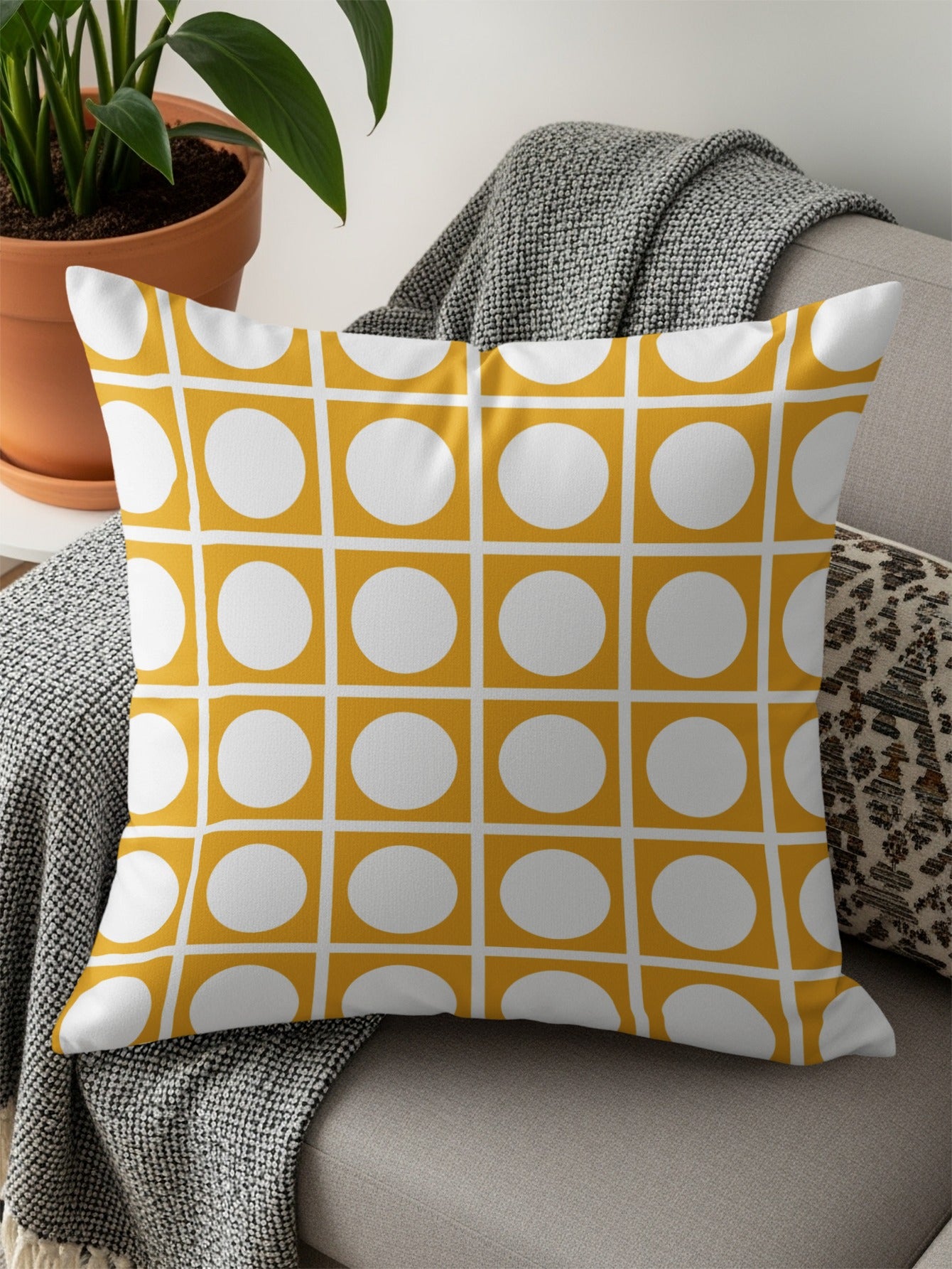 Yellow throw pillow with white circles in a grid pattern on a couch.