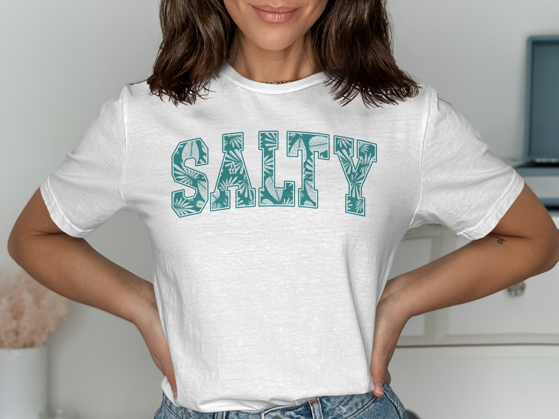 White t-shirt with "SALTY" text in a palm leaf pattern.