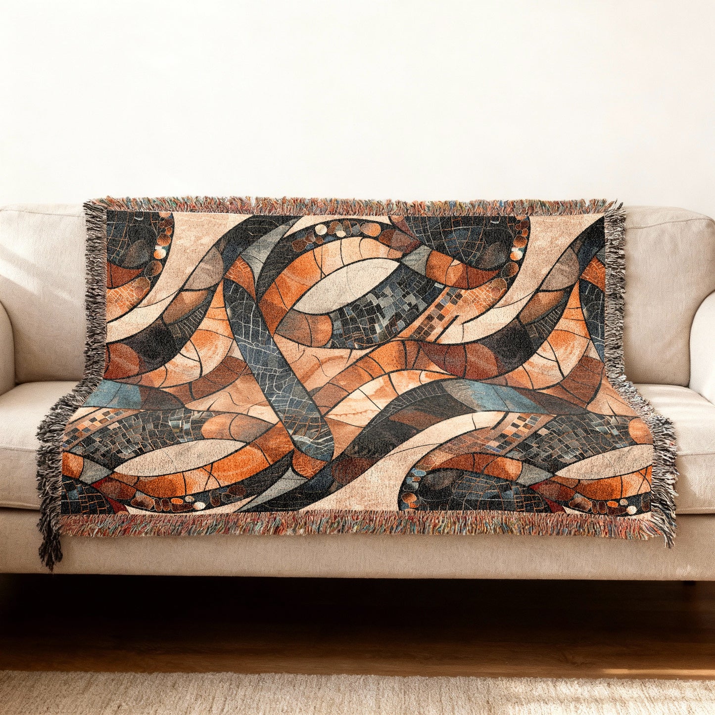 Woven throw blanket with abstract mosaic pattern in earth tones on a sofa.