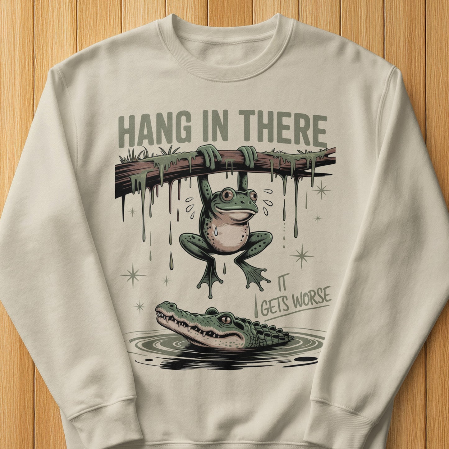Frog hanging from branch above alligator, text "HANG IN THERE IT GETS WORSE".