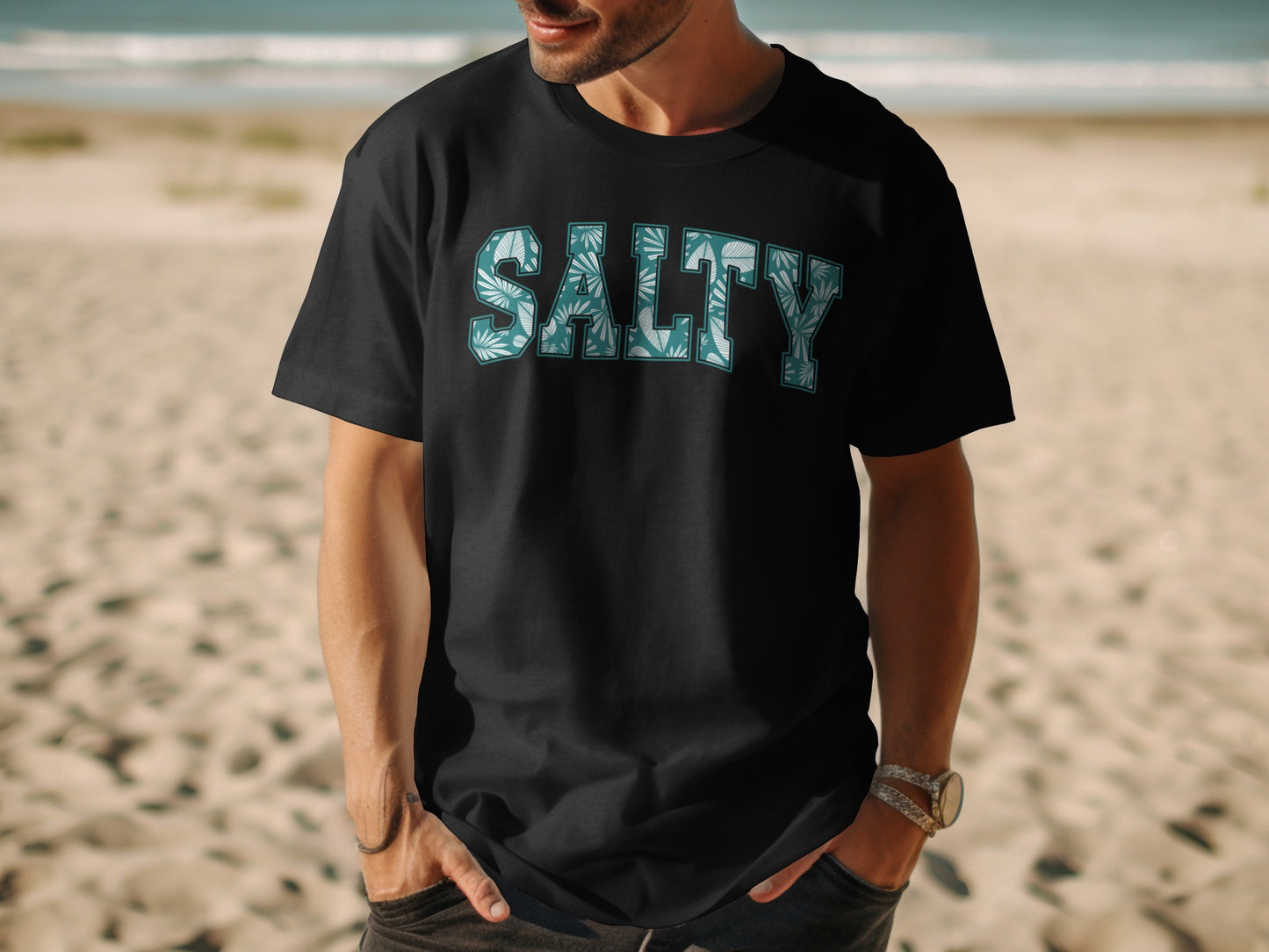 Black t-shirt with "SALTY" text featuring a tropical leaf pattern.