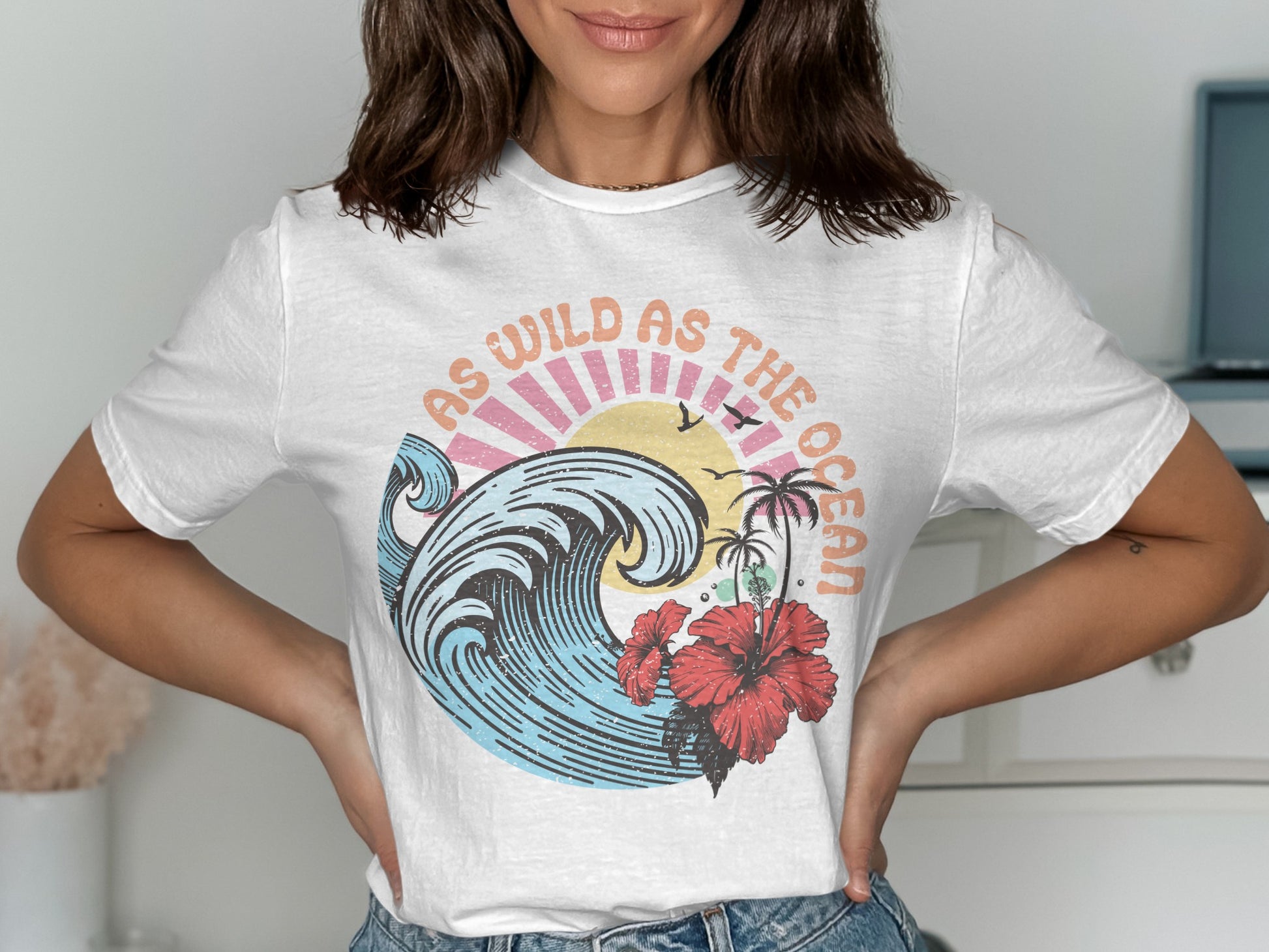 White t-shirt with "As Wild As The Ocean" text and a tropical wave graphic.