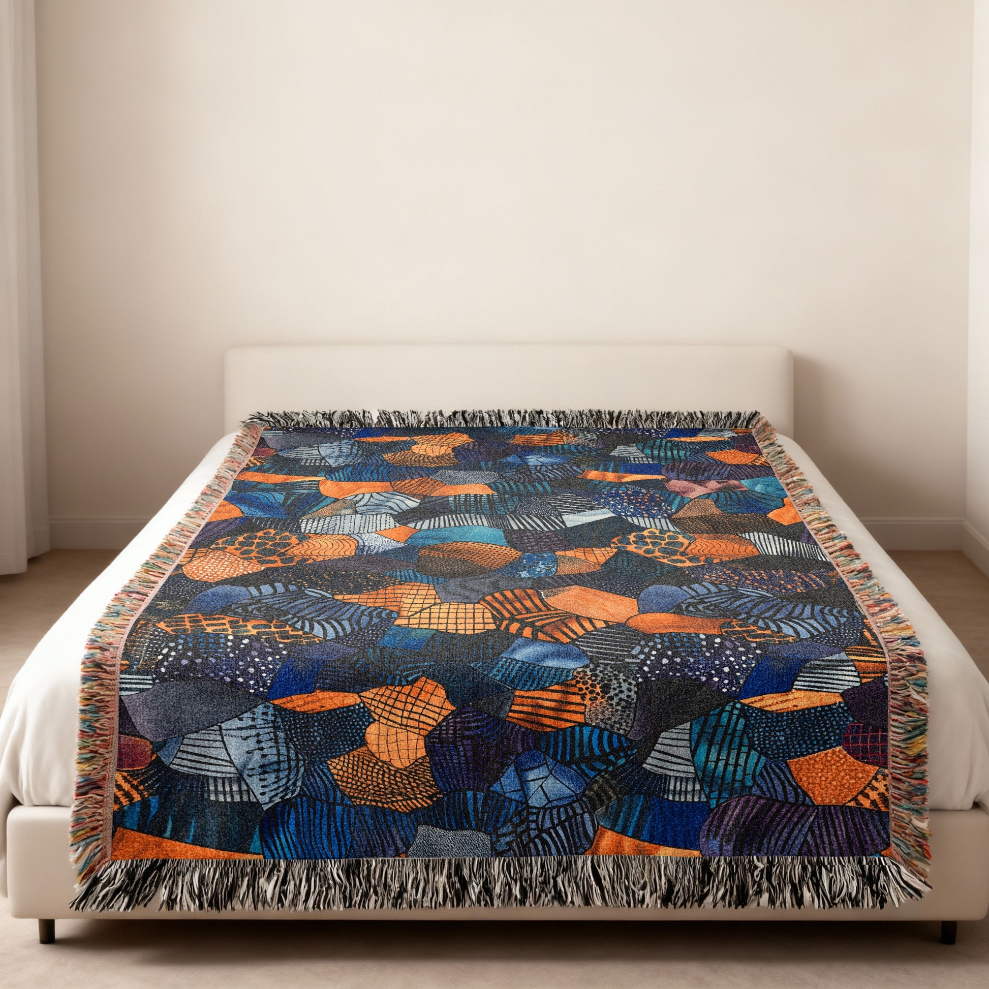 Woven blanket with a colorful abstract geometric pattern on a bed.