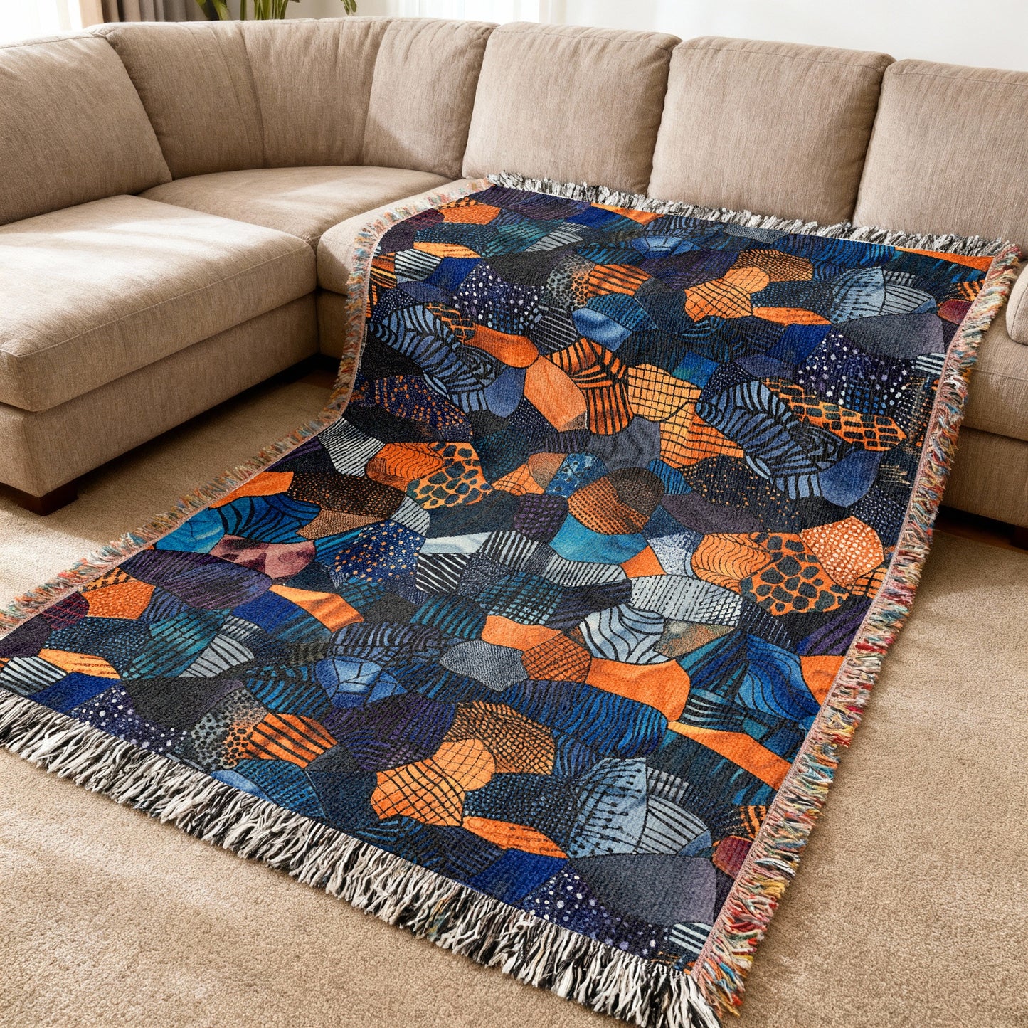 Colorful abstract patterned throw blanket with fringe on a sectional sofa.