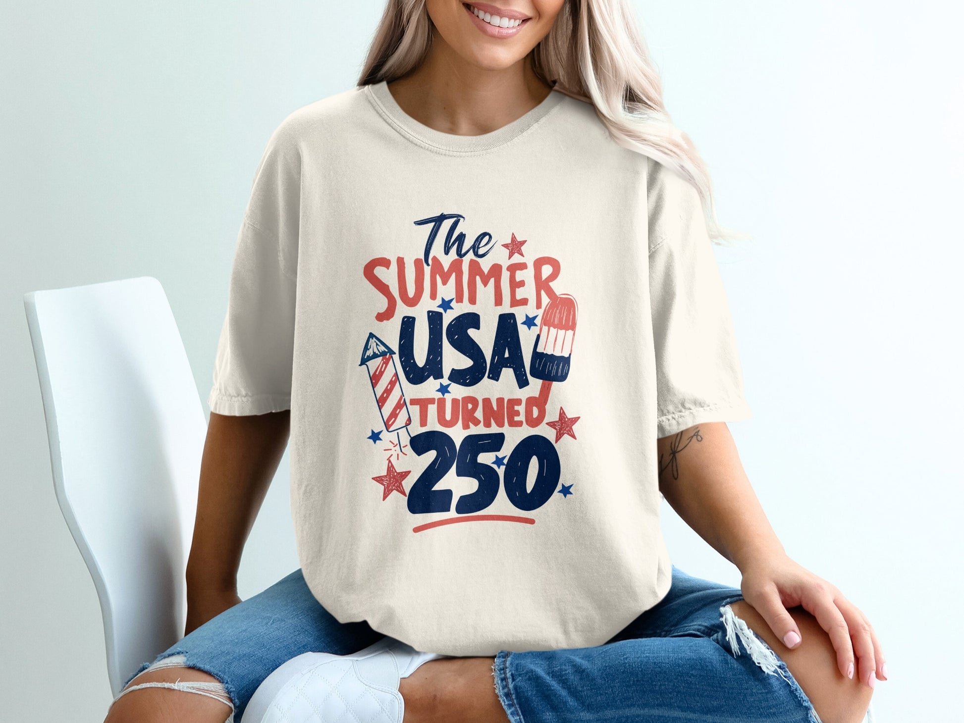 Cream t-shirt with "The Summer USA Turned 250" text, fireworks, and popsicle.