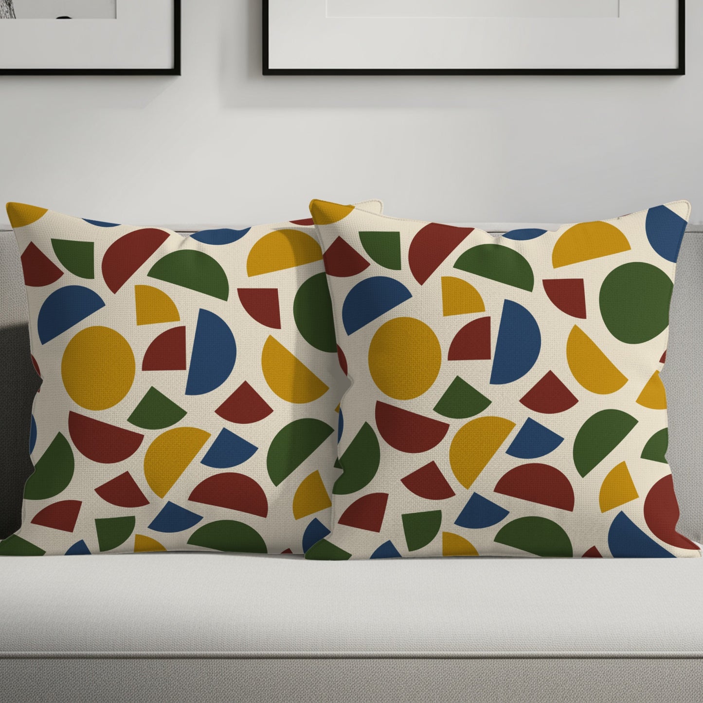 Two cream throw pillows with a colorful geometric pattern of circles and arcs.