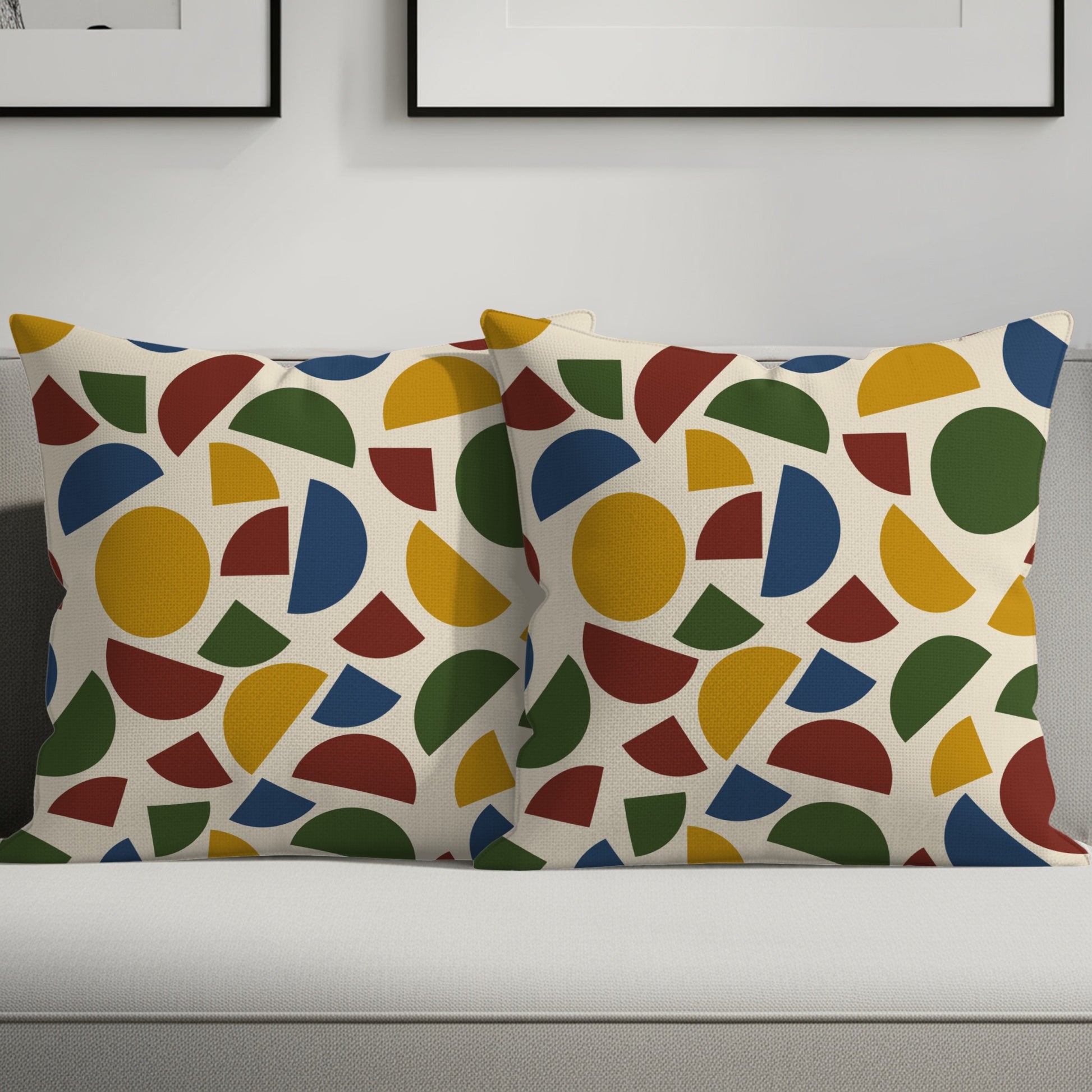 Two cream throw pillows with a colorful geometric pattern of circles and arcs.