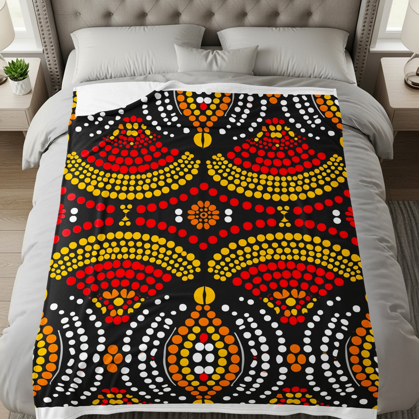 Black blanket with red, yellow, and white dot art pattern on a bed.