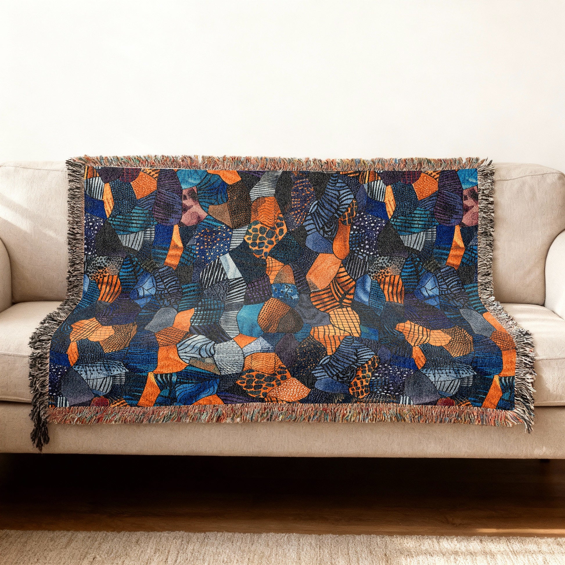 Woven throw blanket with abstract geometric pattern in blue, orange and navy.