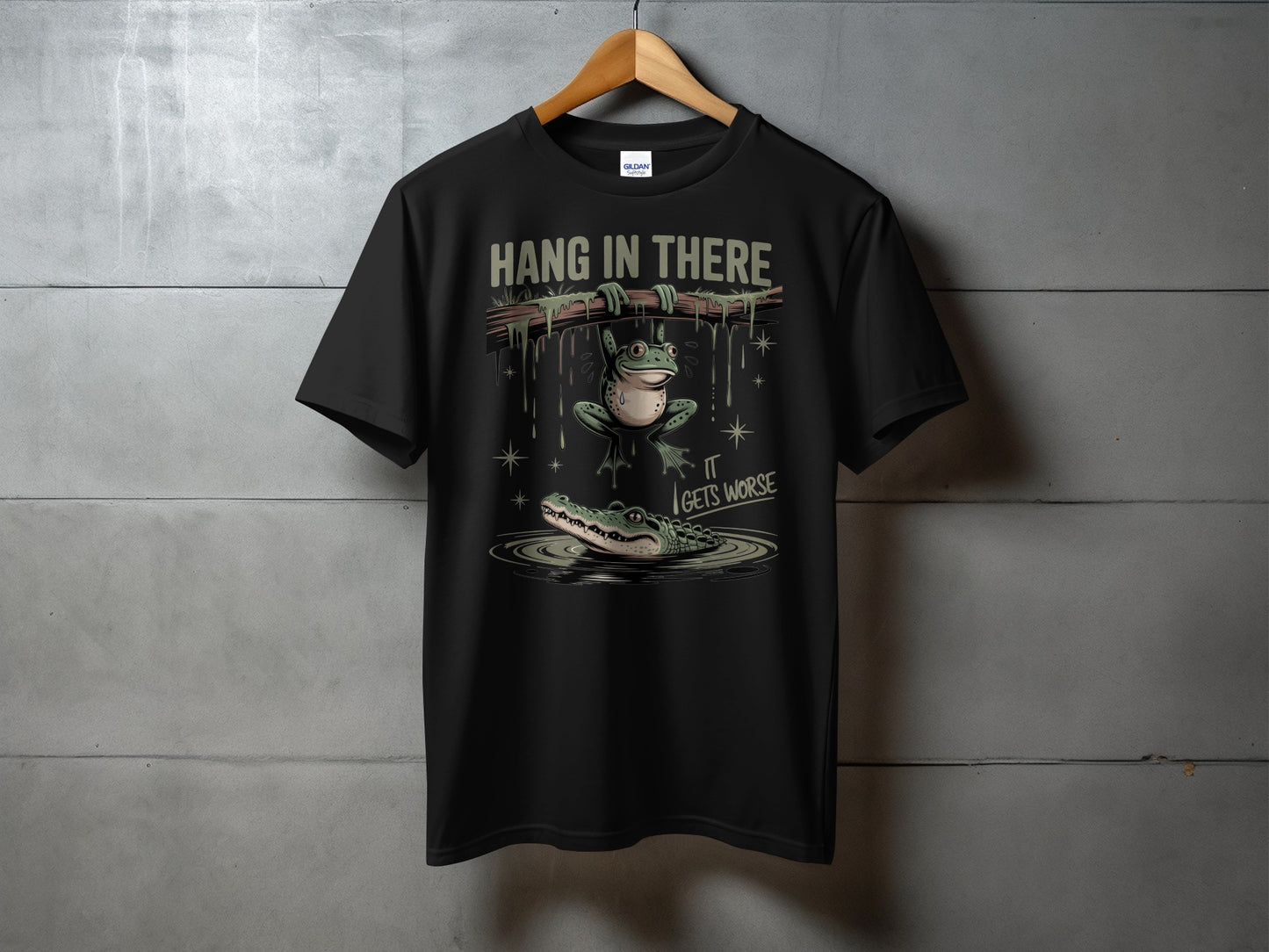 Black t-shirt with a frog hanging from a branch above an alligator.