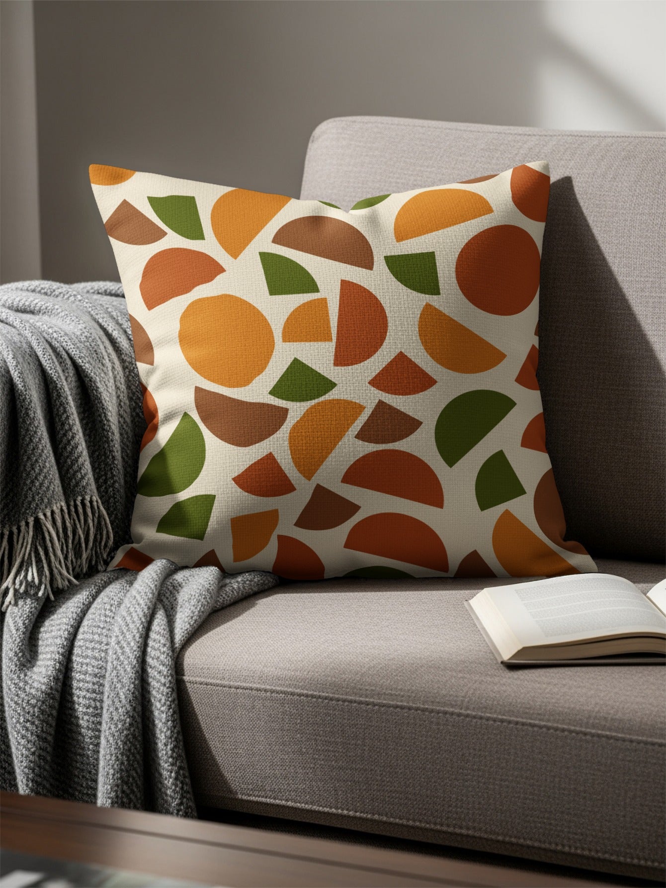 Throw pillow with abstract scattered circles and semi-circles in autumn colors on a sofa.