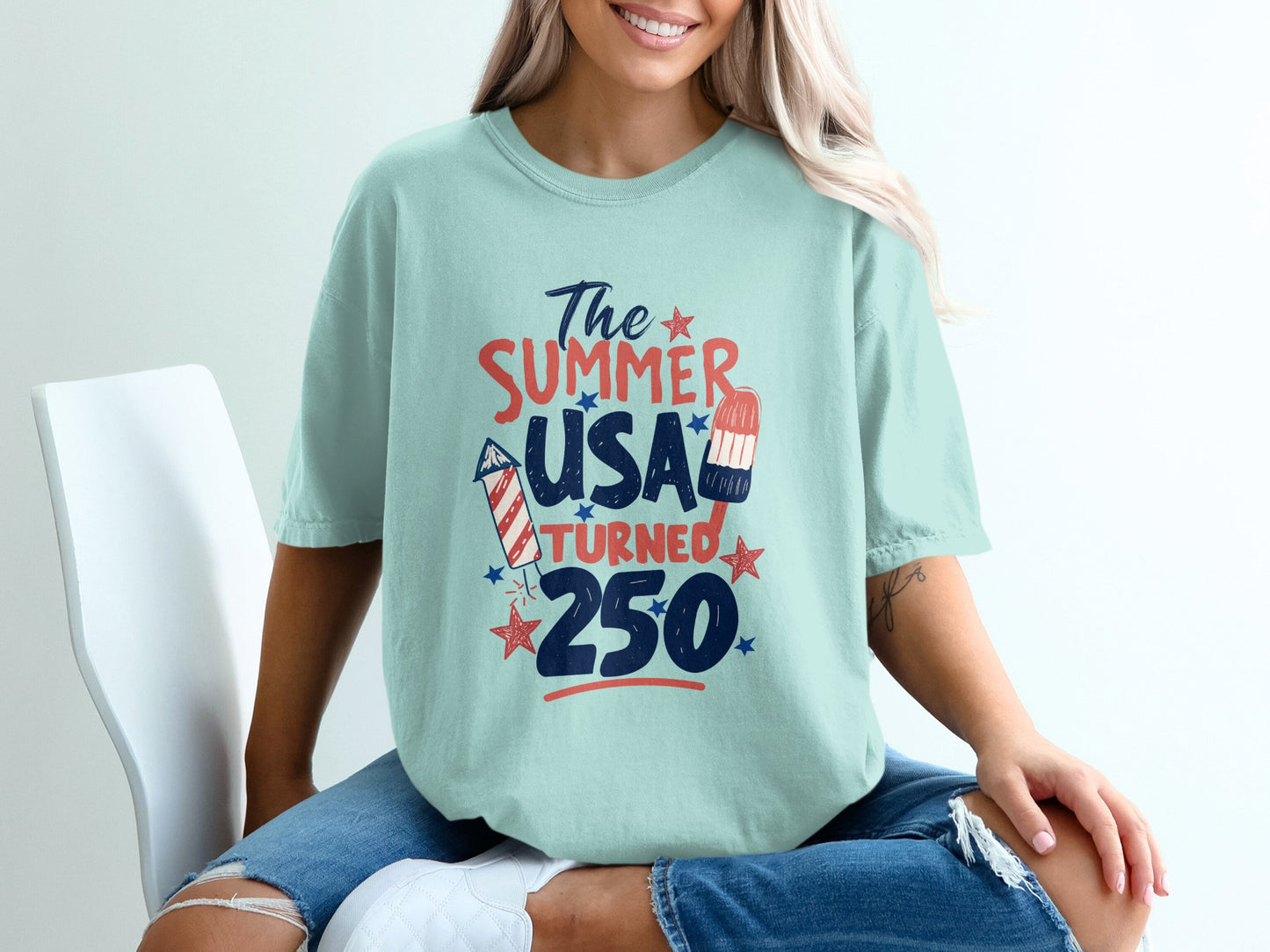 Teal t-shirt with "The Summer USA Turned 250" text and patriotic graphics.