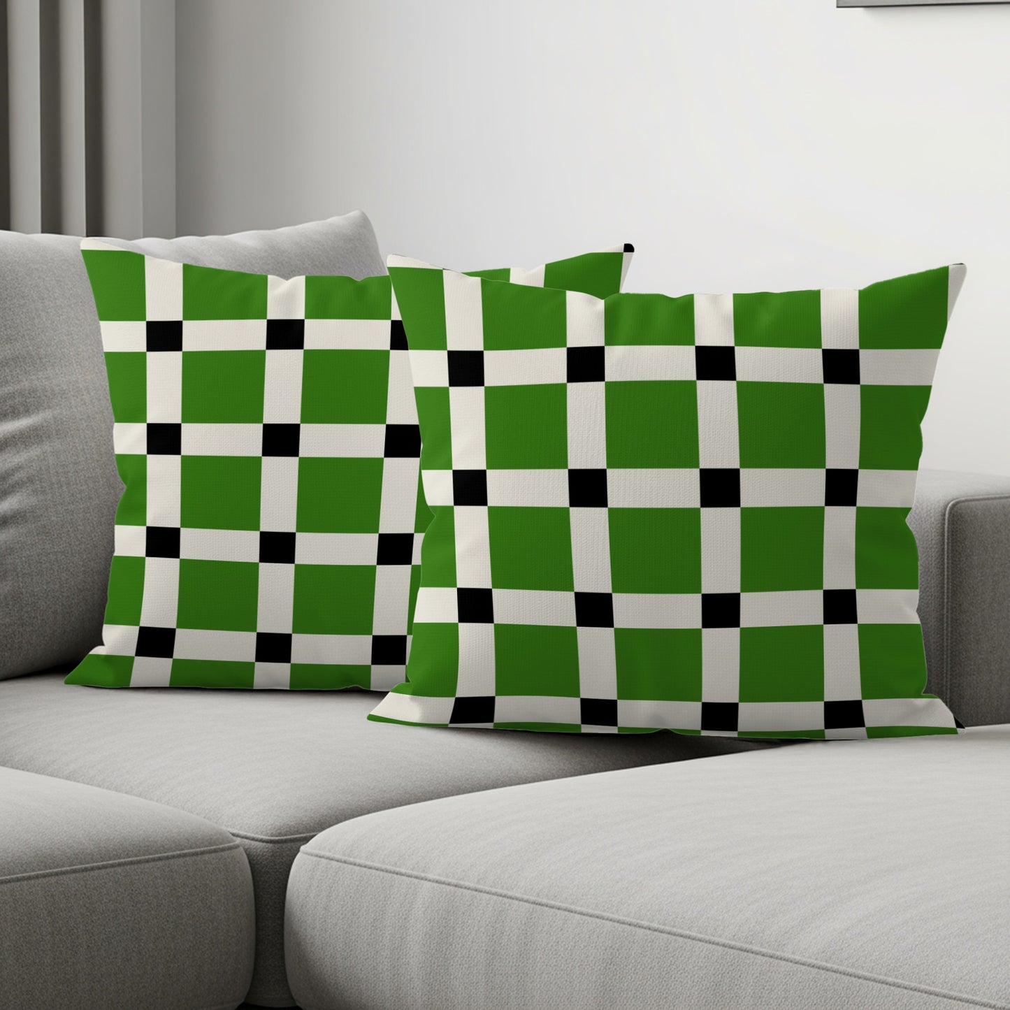 Two throw pillows with a green, white, and black checkered pattern on a sofa.