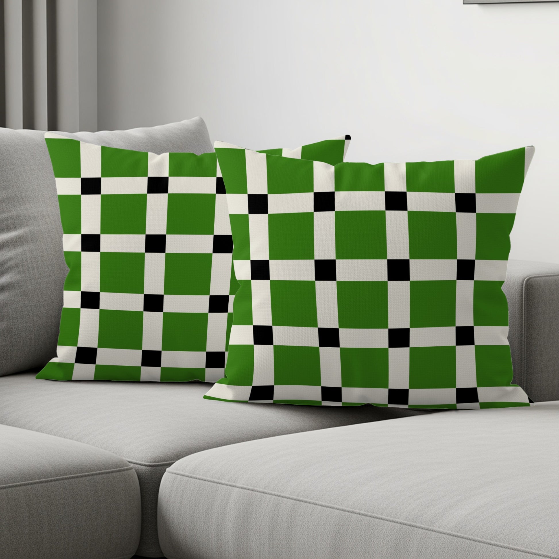 Two throw pillows with a green, white, and black checkered pattern on a sofa.
