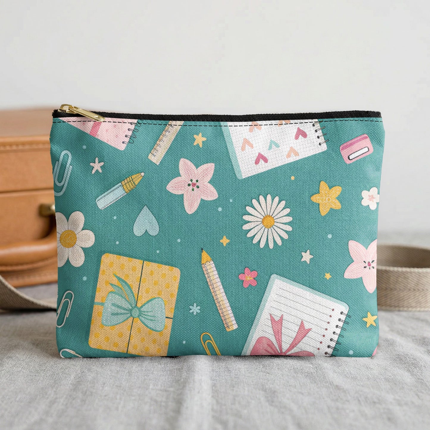 Teal pouch with scattered school supplies and floral pattern.