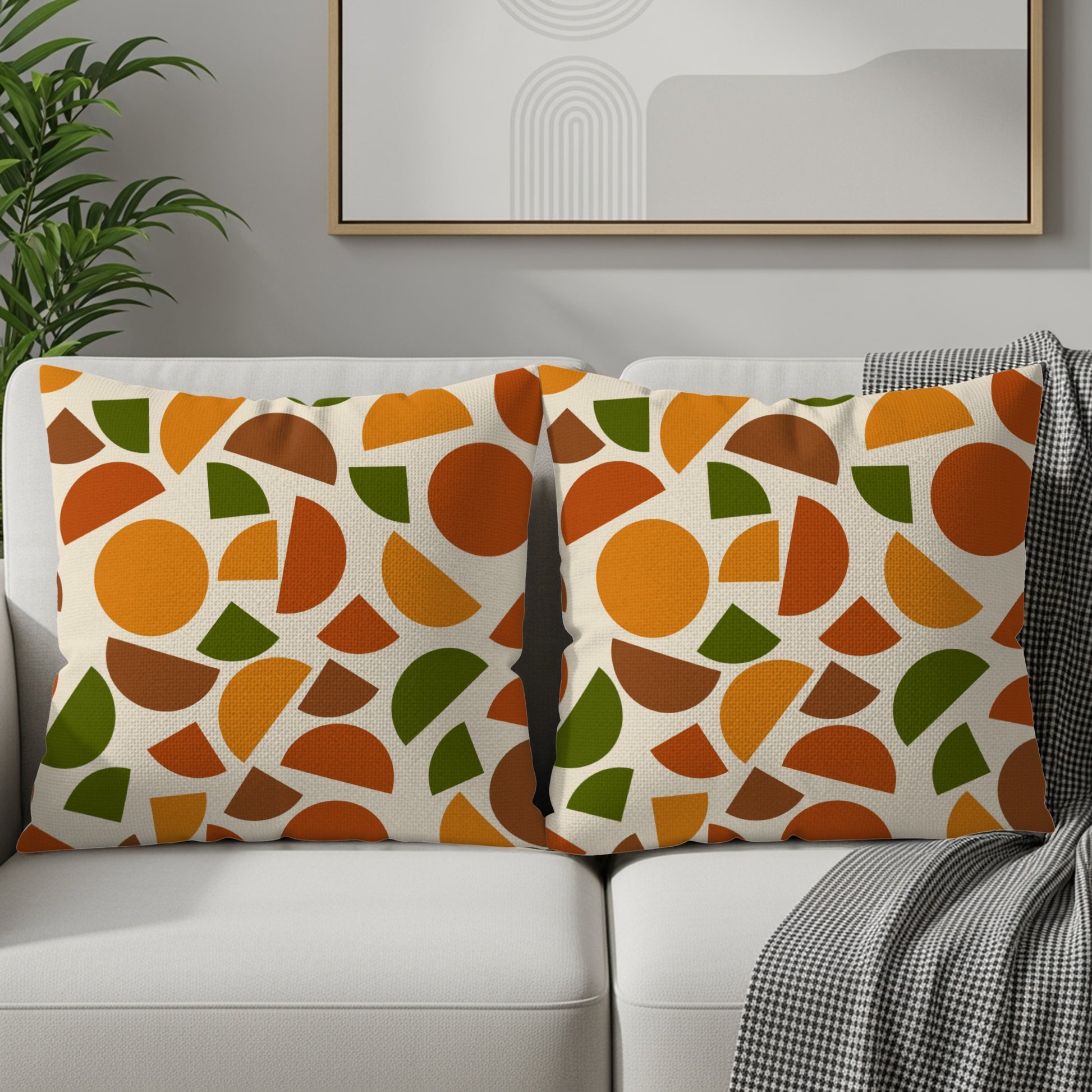 Two throw pillows with a geometric pattern of circles and semicircles in orange and green on a cream background.
