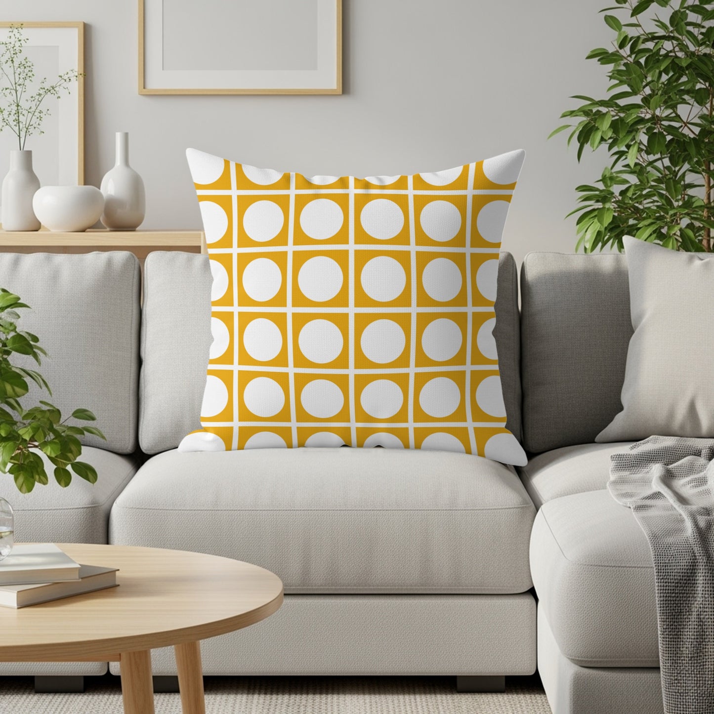 Yellow throw pillow with a grid of white circles on a light gray couch.