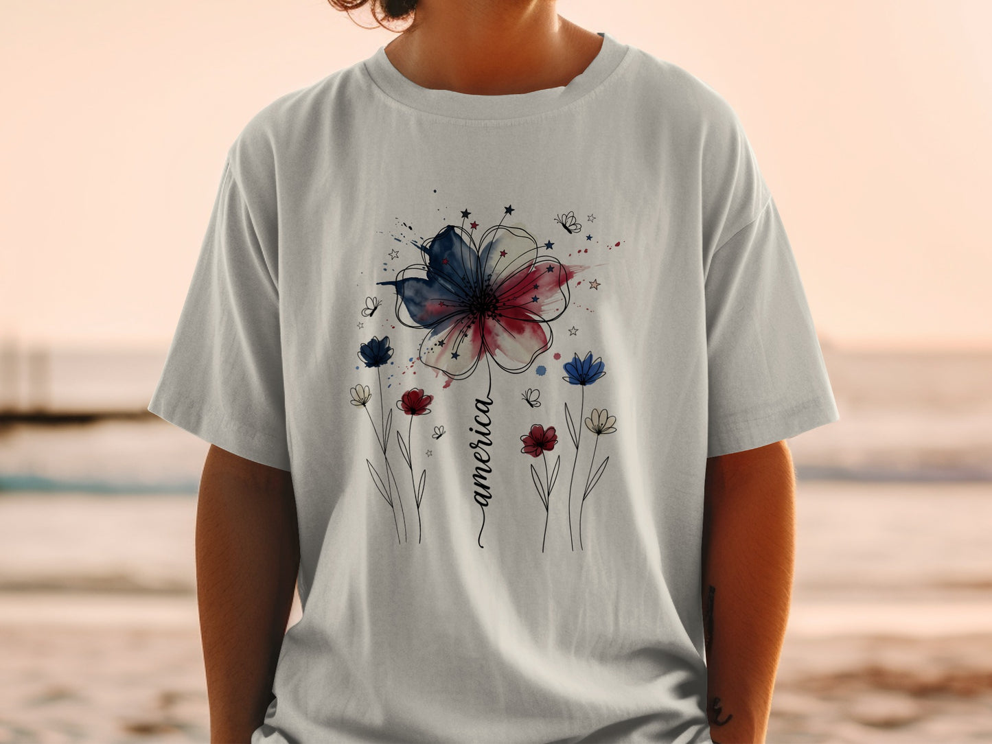 White t-shirt with red, white, and blue watercolor flower and "America" text.