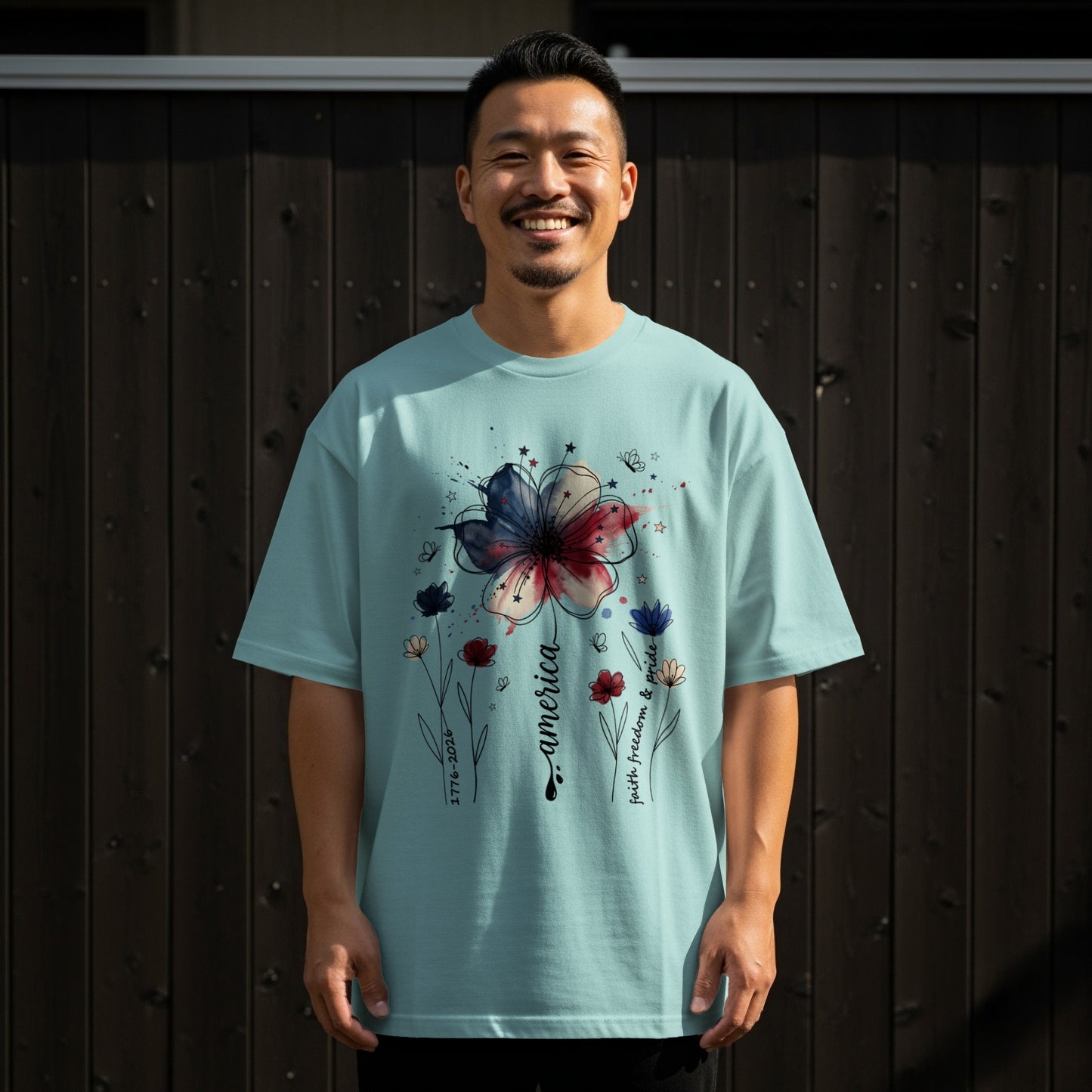 Man wearing light blue t-shirt with patriotic flower graphic and text.