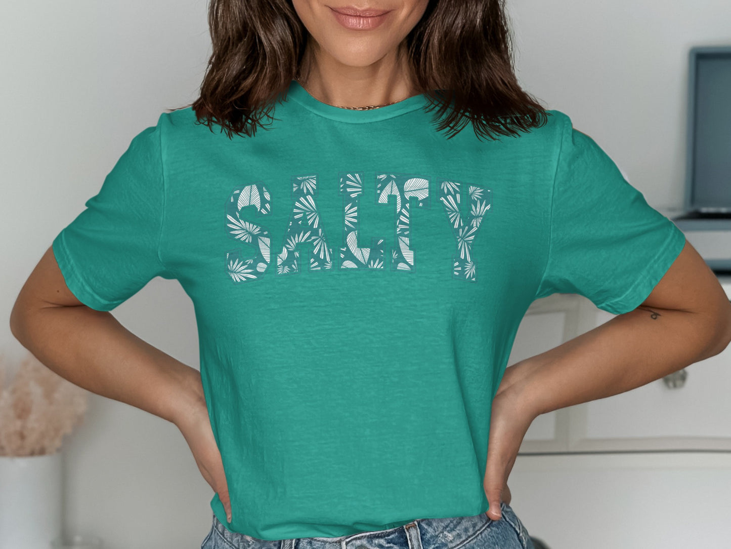 Teal t-shirt with "SALTY" text in a tropical leaf pattern.