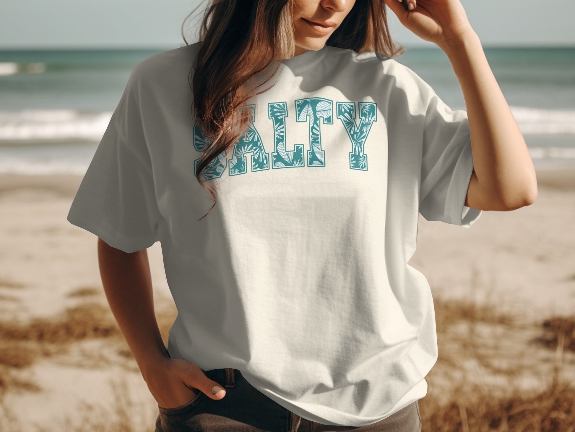White t-shirt with blue "Salty" text featuring tropical leaf pattern.