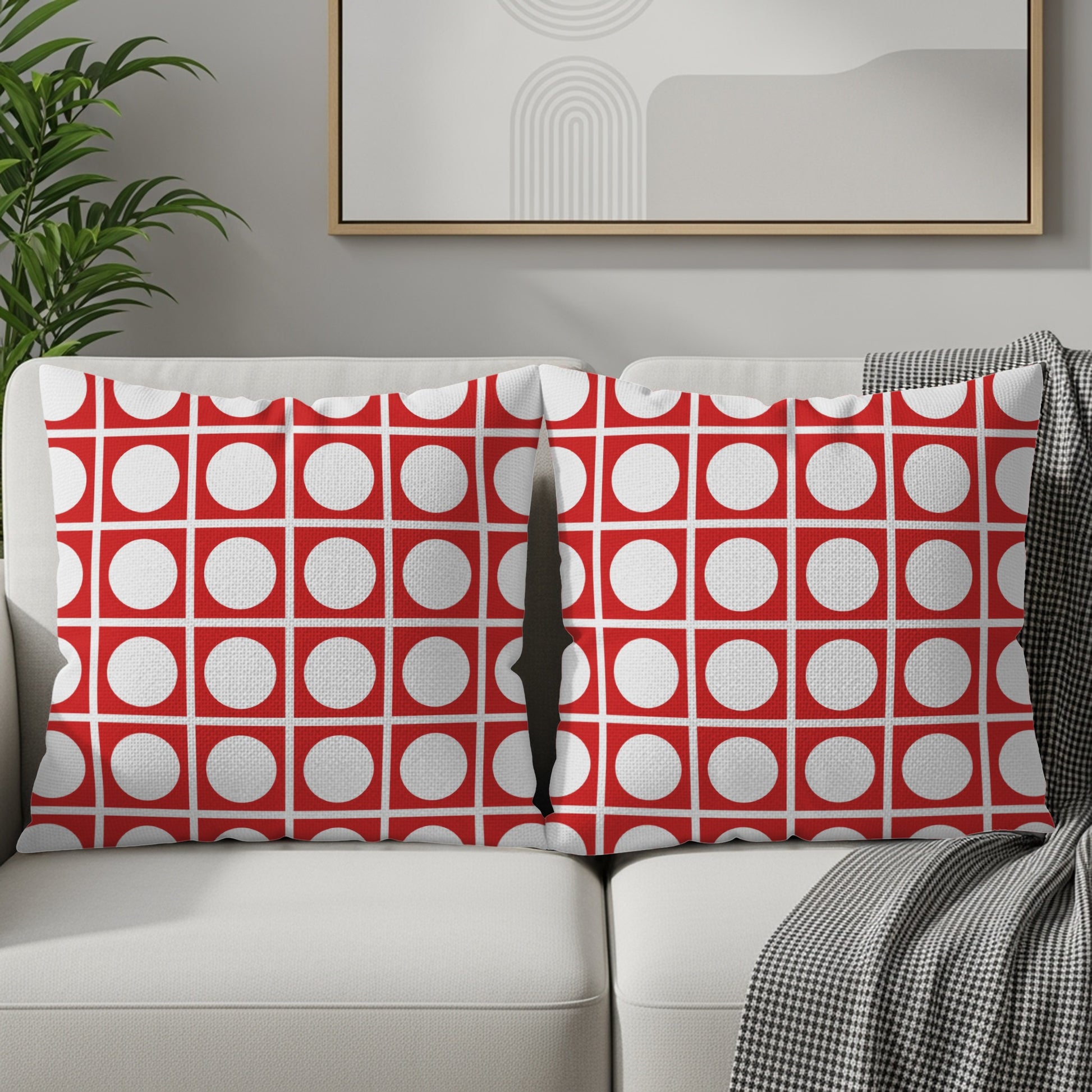 Two pillows with a red and white geometric circle pattern rest on a sofa.
