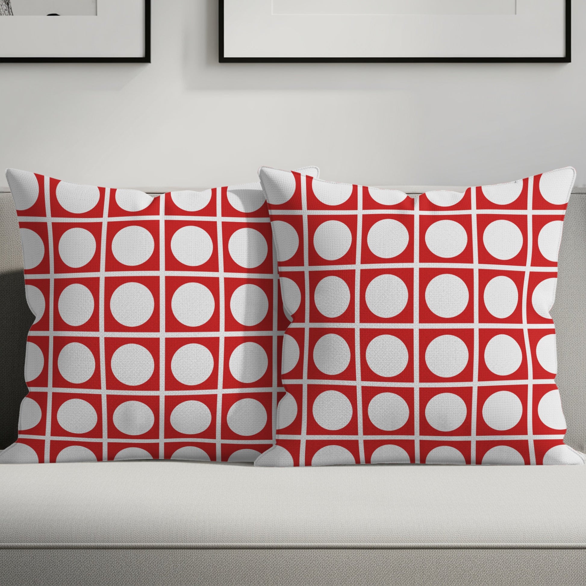 Two decorative pillows with a red and white geometric circle pattern sit on a couch.