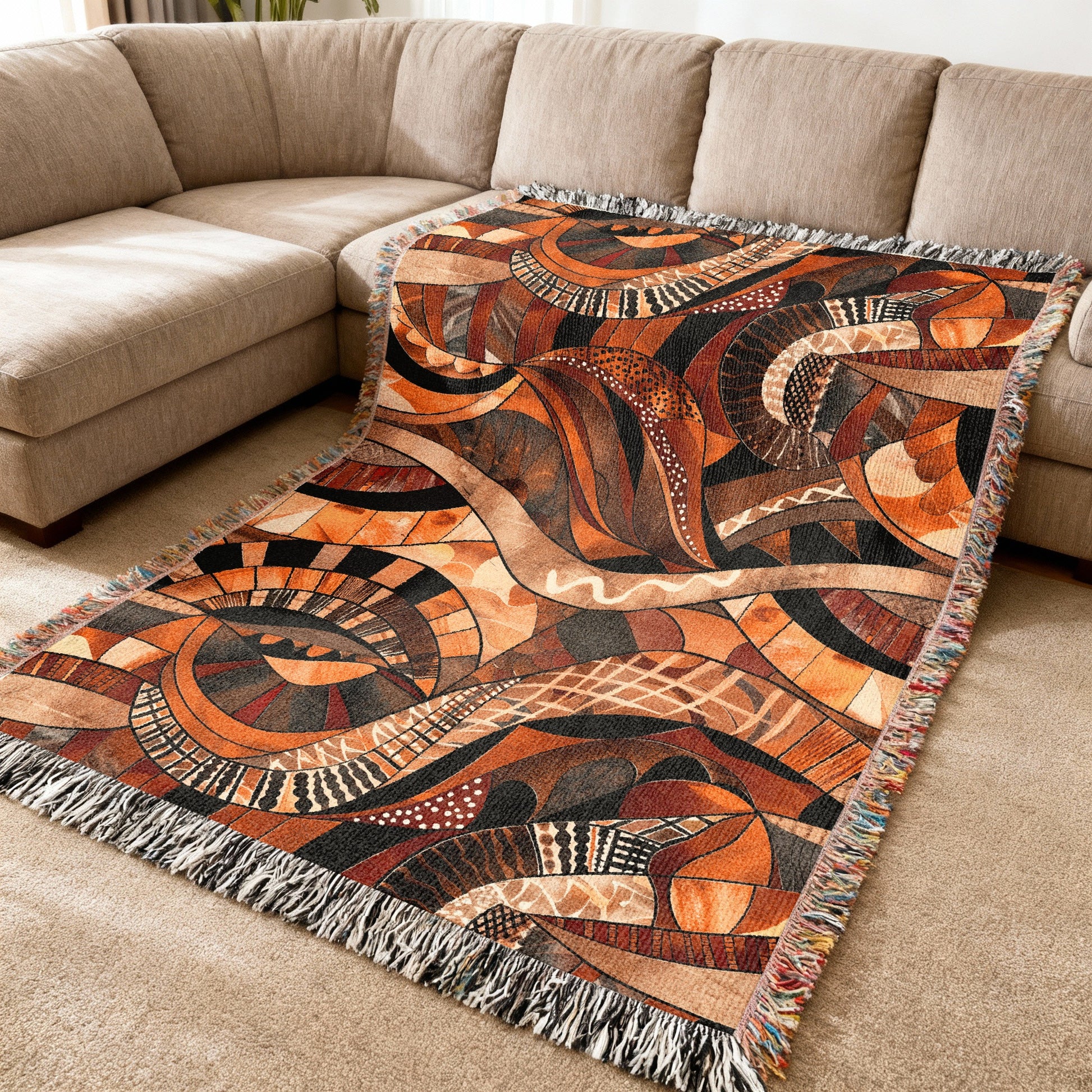Woven throw blanket with abstract geometric pattern in warm earth tones.