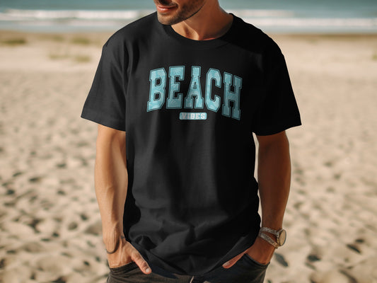 Black t-shirt with "BEACH VIBES" text on a man standing on a beach.