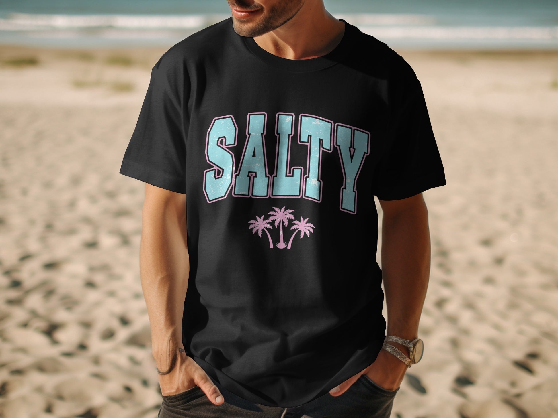 Black t-shirt with "SALTY" text and pink palm trees, worn by a man.