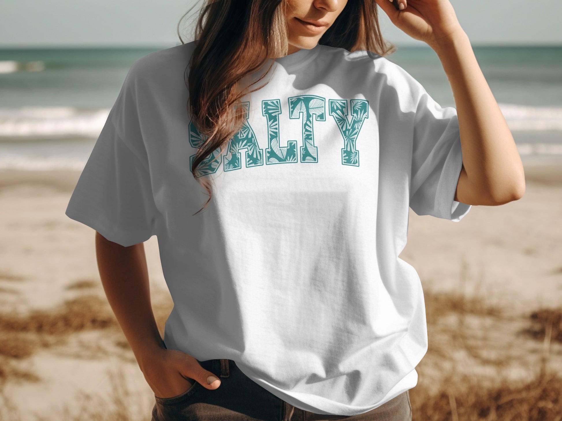 White t-shirt with "SALTY" printed in a tropical leaf pattern.