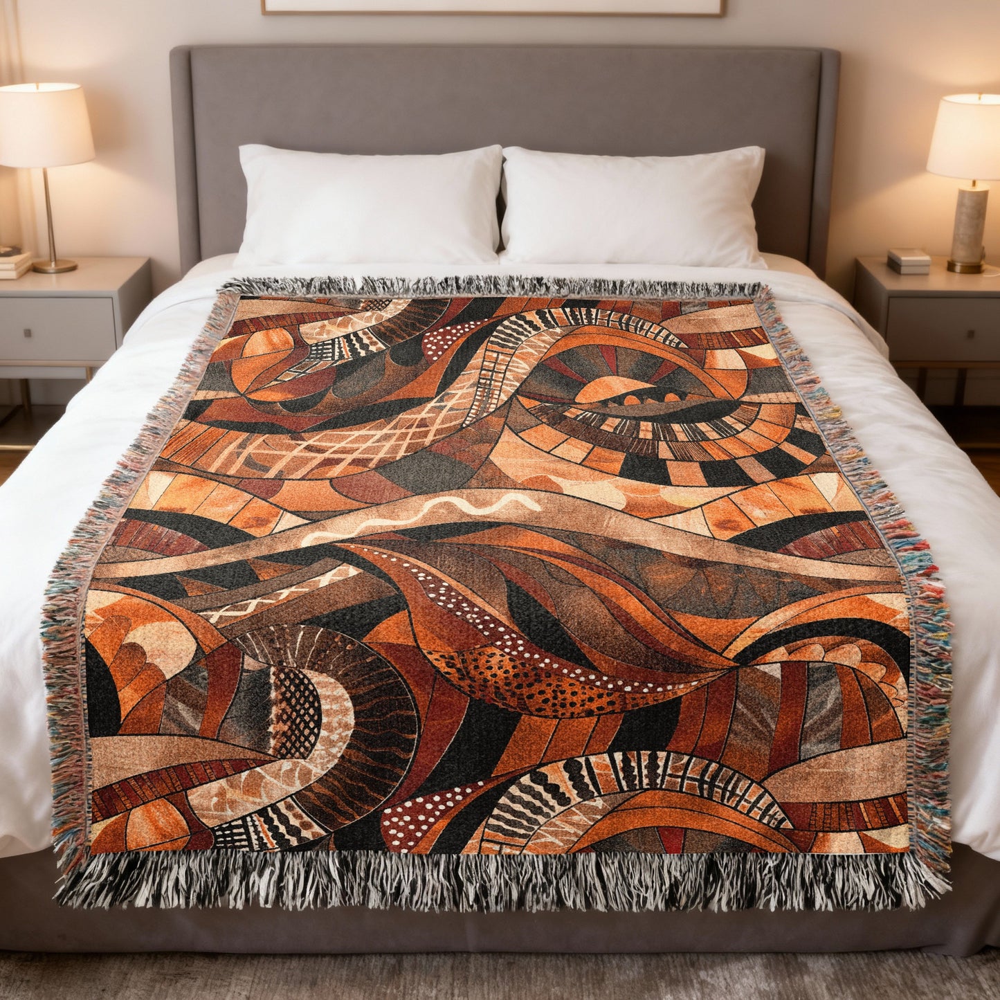 Woven throw blanket with abstract organic pattern in warm earth tones on bed.