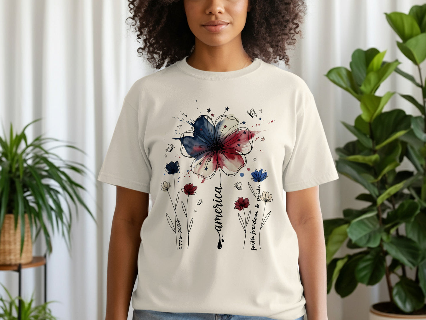 Cream t-shirt with watercolor American flag flower and "America faith freedom & pride" text.