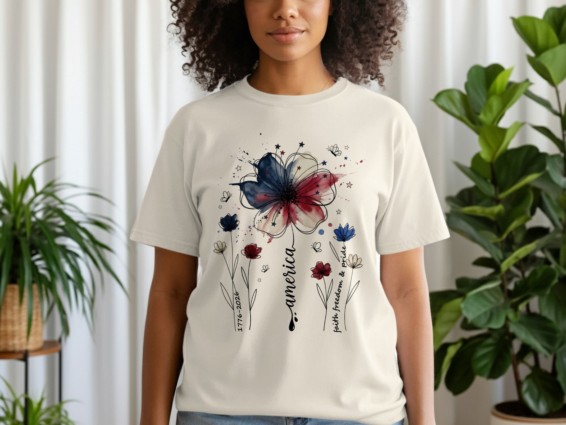 Cream t-shirt with watercolor American flag flower and "America faith freedom & pride" text.