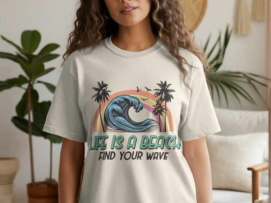 T-shirt with rainbow, wave, and palm trees graphic; text "LIFE IS A BEACH FIND YOUR WAVE".