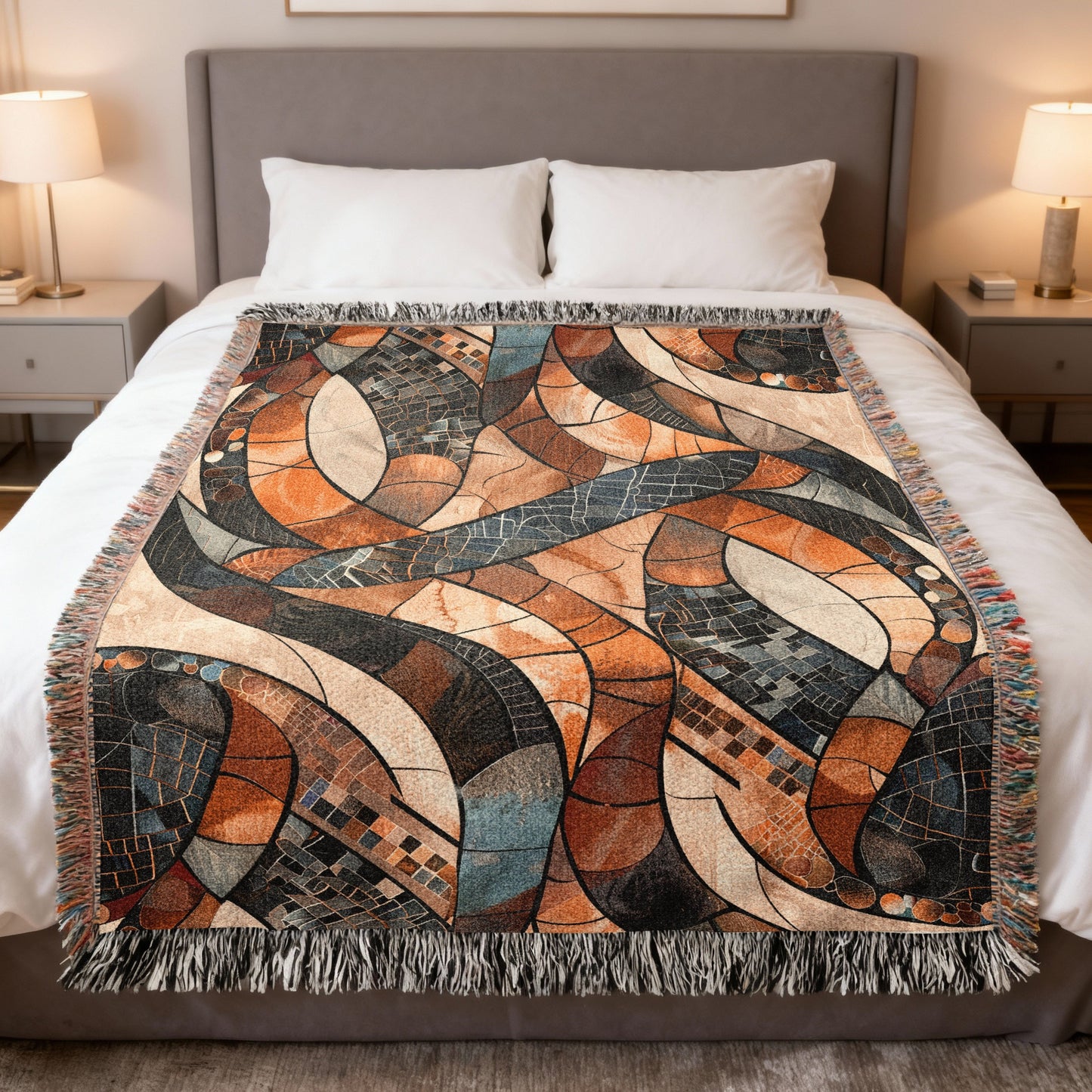 Abstract geometric woven throw blanket in shades of orange, brown, and blue with fringe.